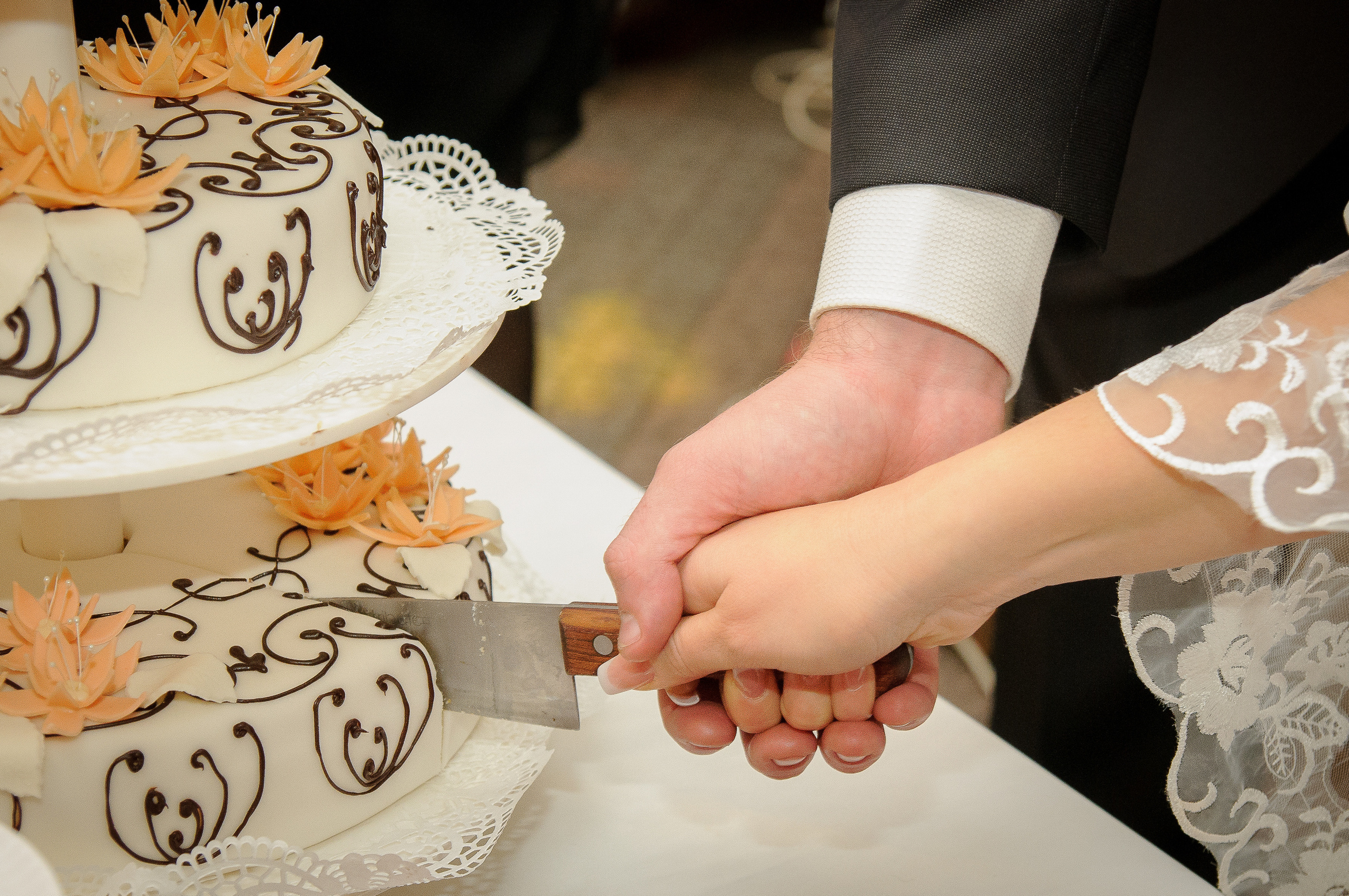 Жених с невестой режут ножом свадебный торт