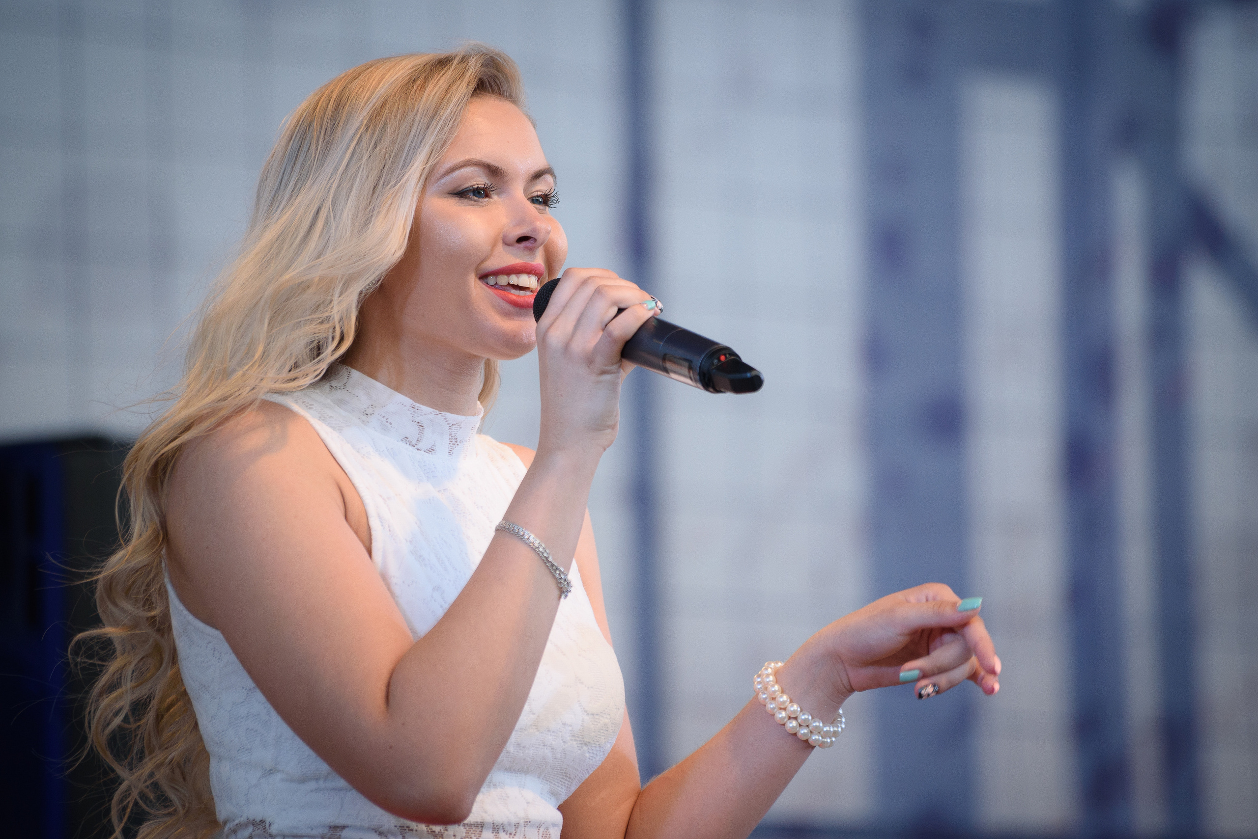 Девушка в белой блузке поет на концерте