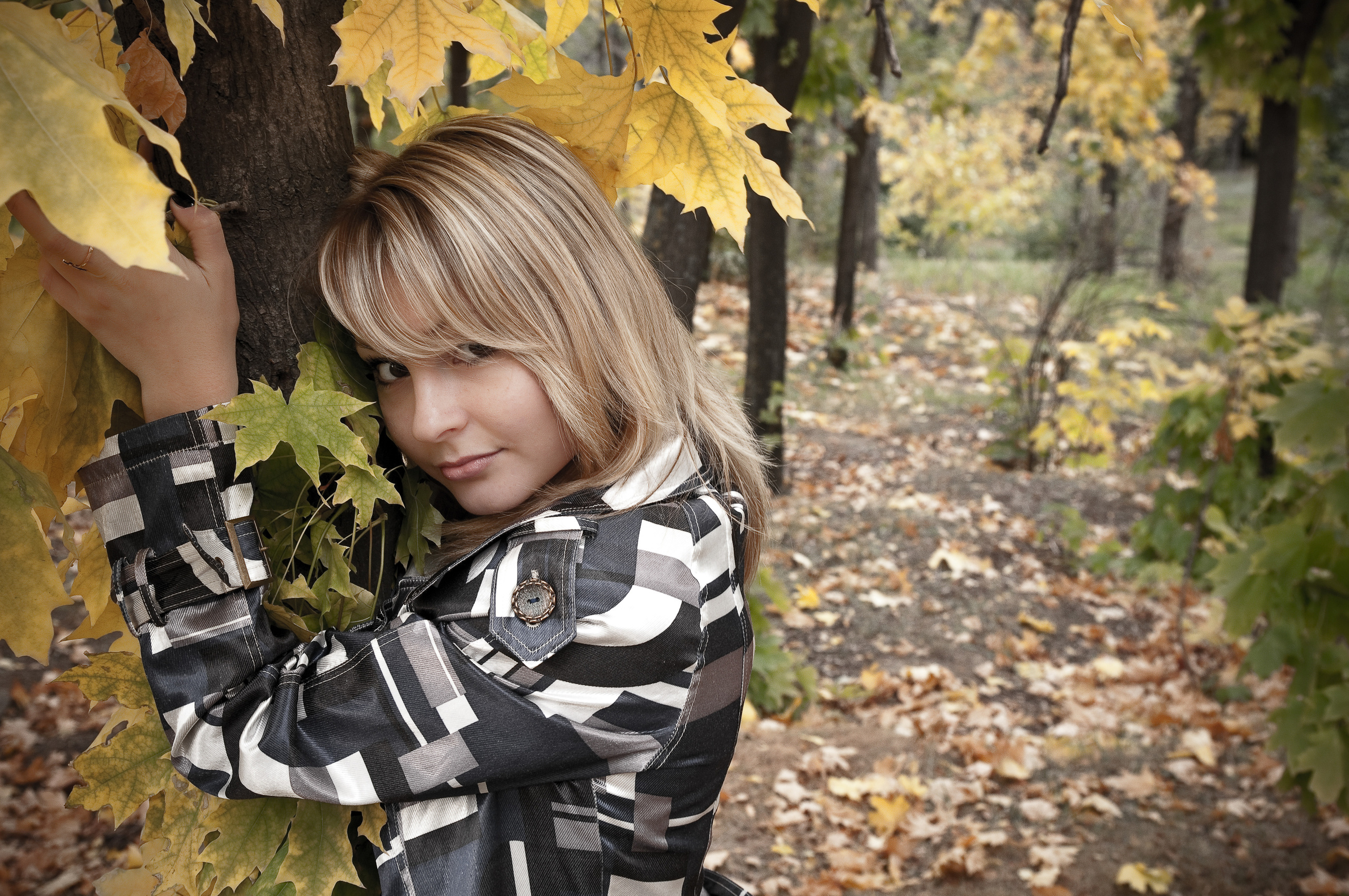 Девушка рядом с клёном с желтыми листьями в осеннем парке
