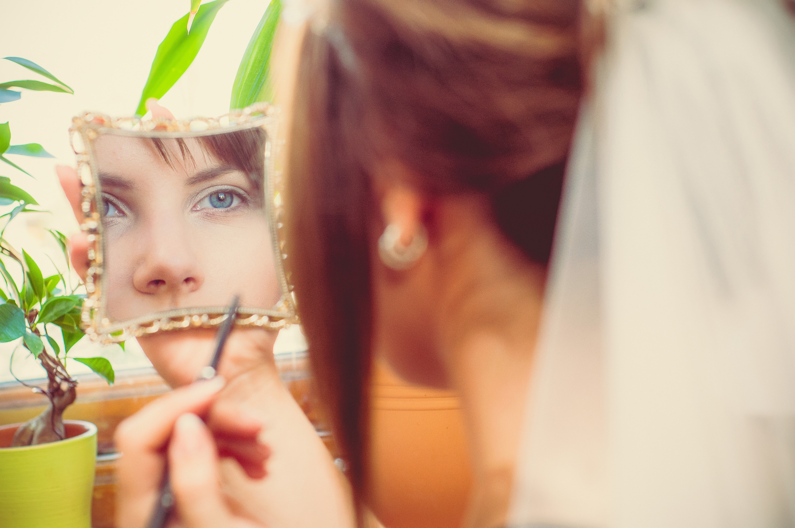 Невеста красит ресницы глядя в своё отражение в зеркале