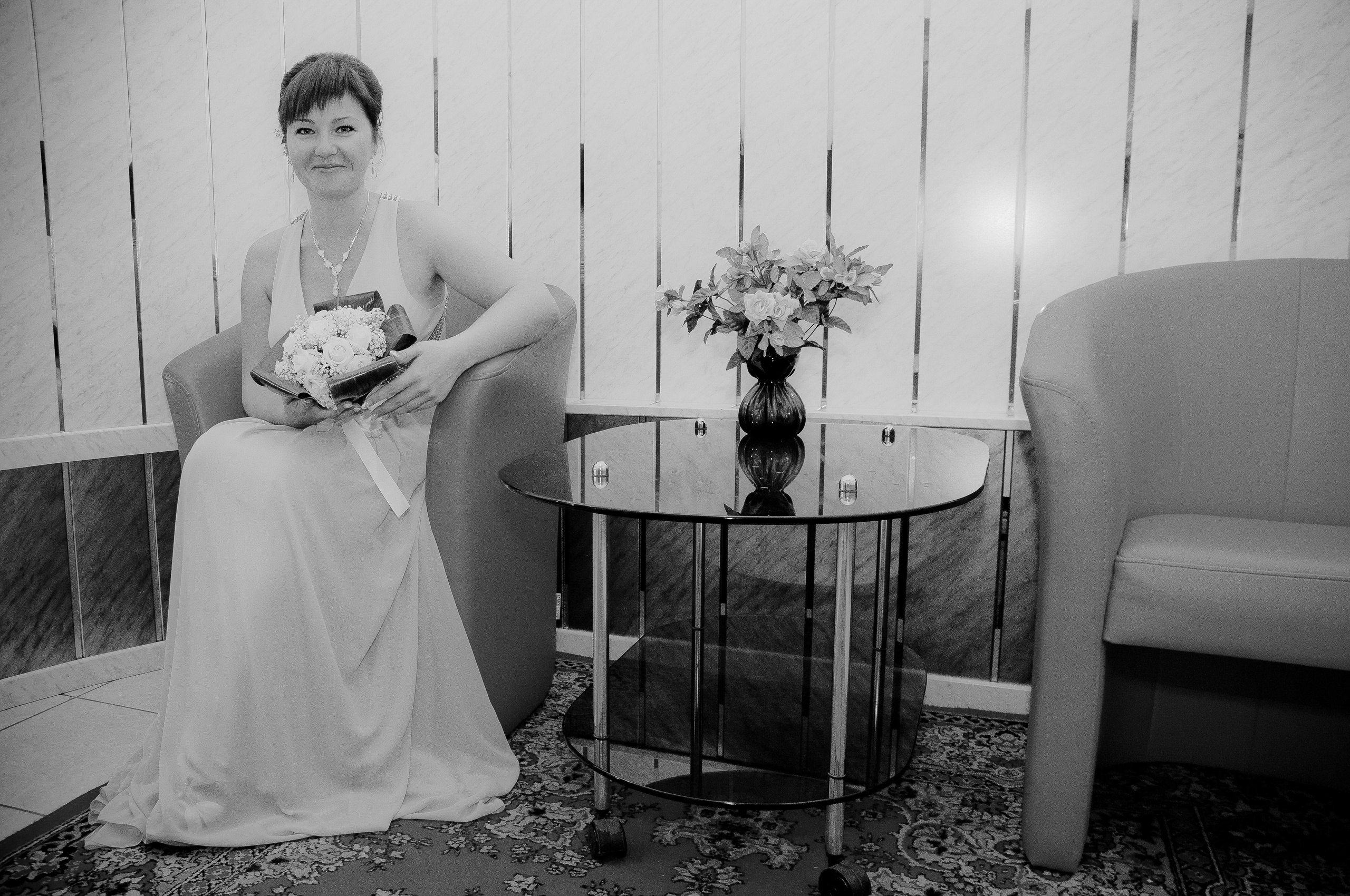Невеста сидит в кресле с букетом цветов около журнального столика