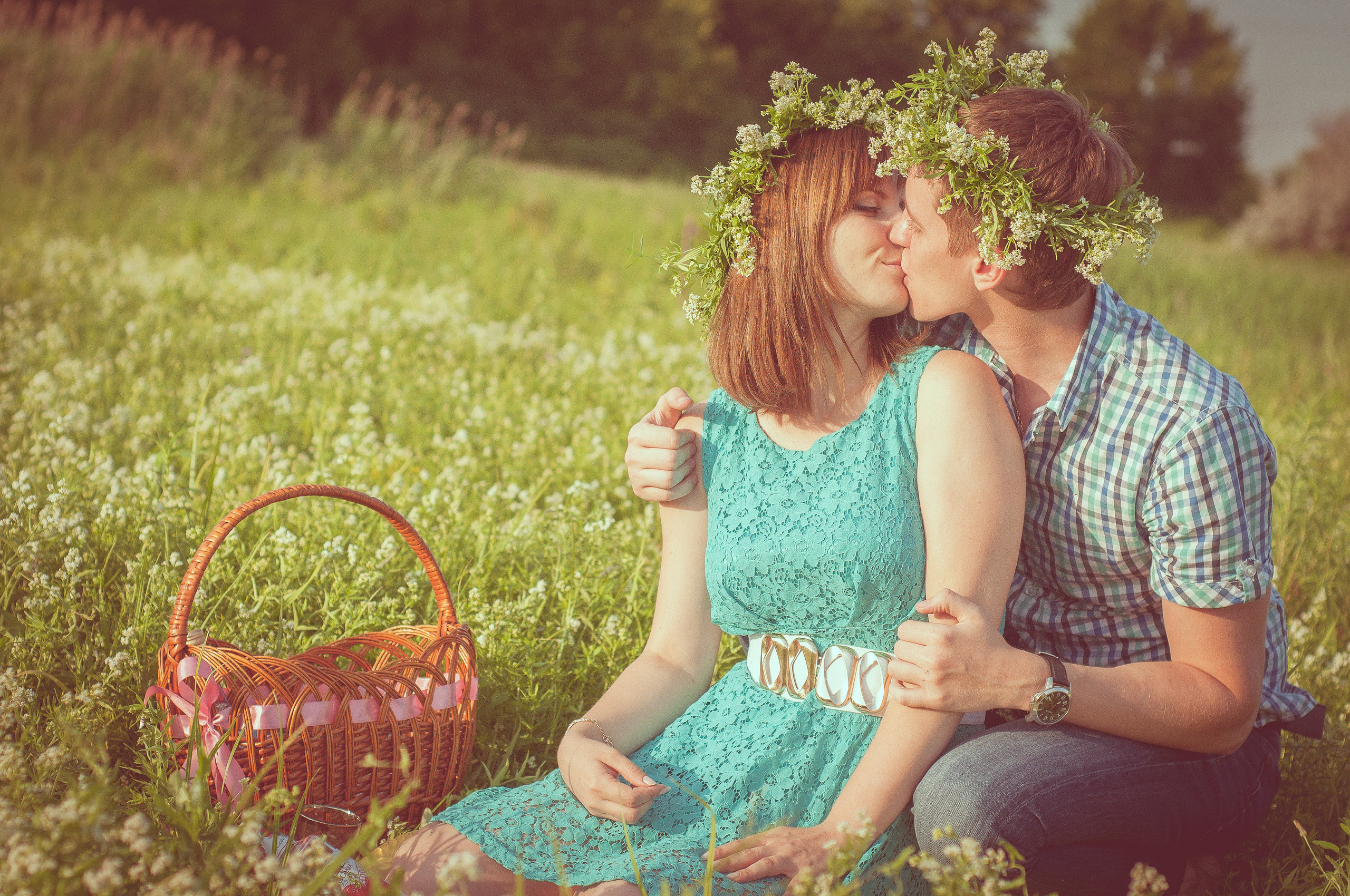 Парень и девушка с венками на голове целуются в цветочном поле