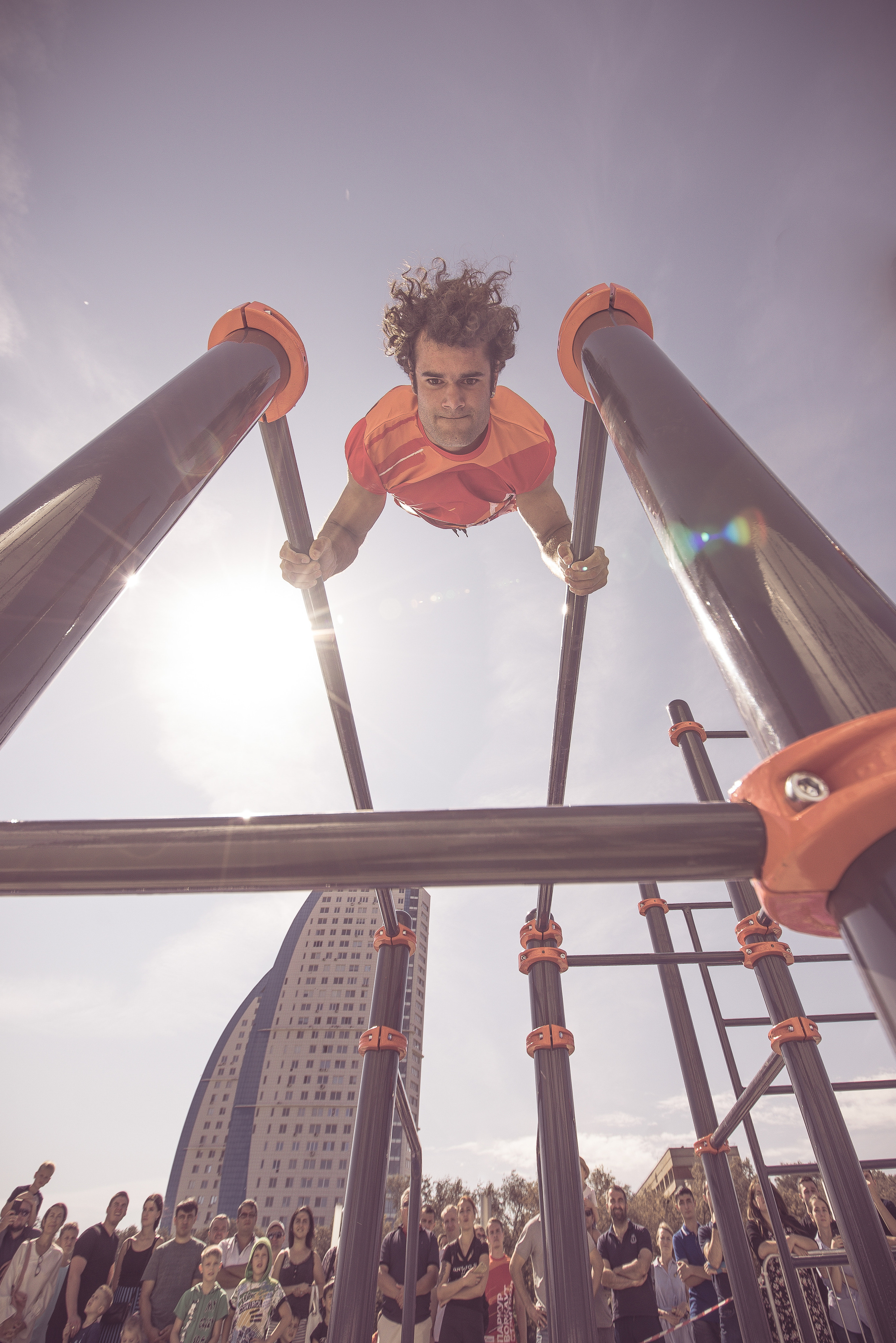 Спортсмен стоит на руках на турнике во время соревнований по воркауту