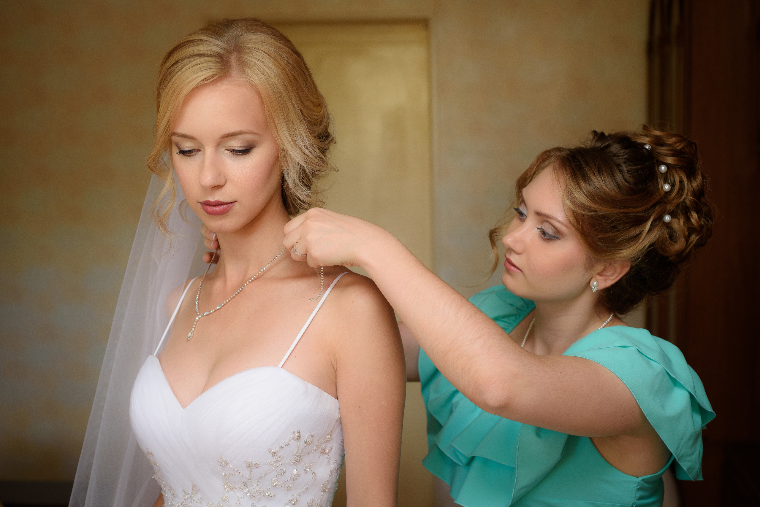 Подруга невесты в бирюзовом платье поправляет фату