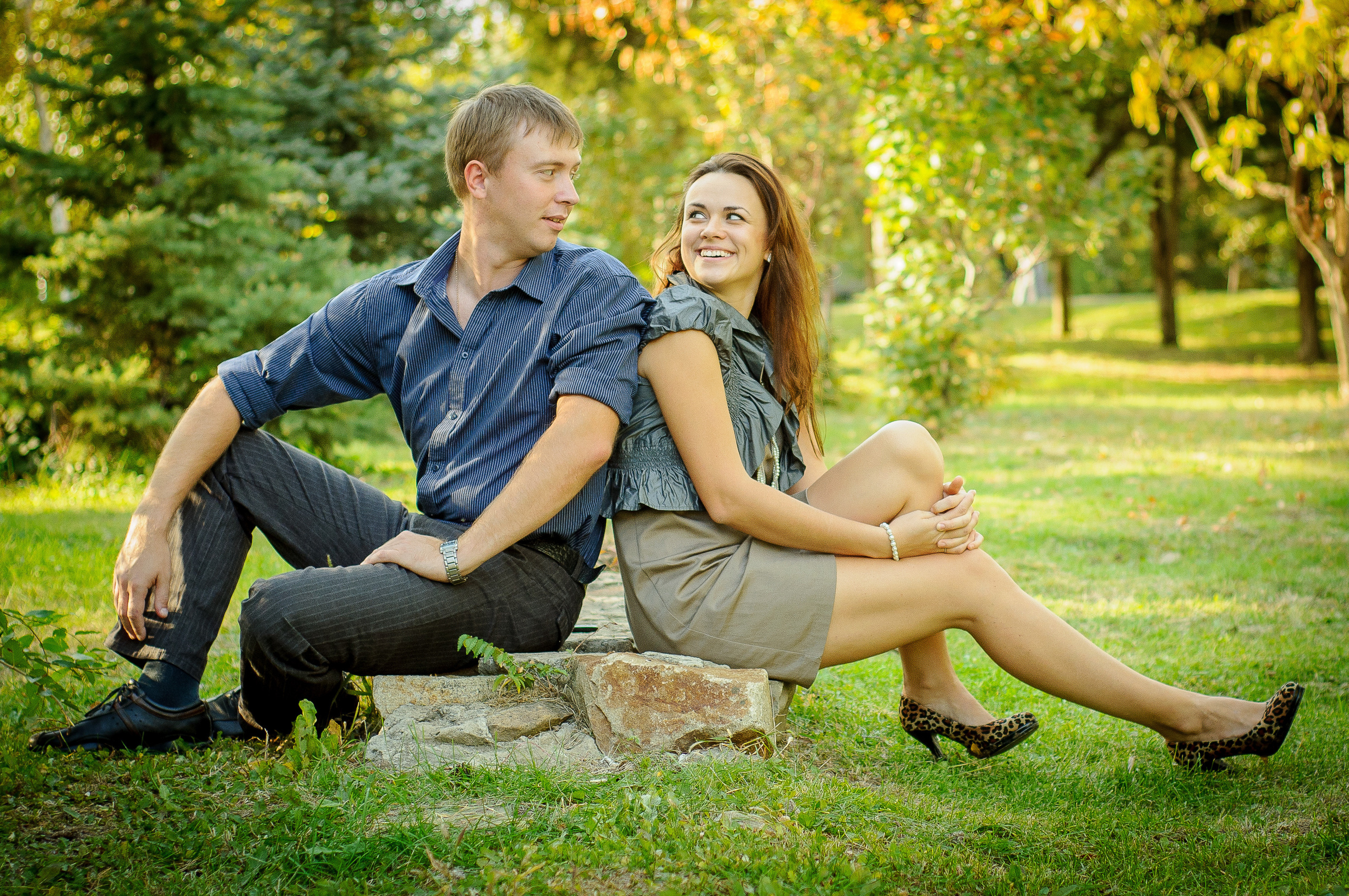 Парень и девушка сидят спина к спине и смотрят друг на друга