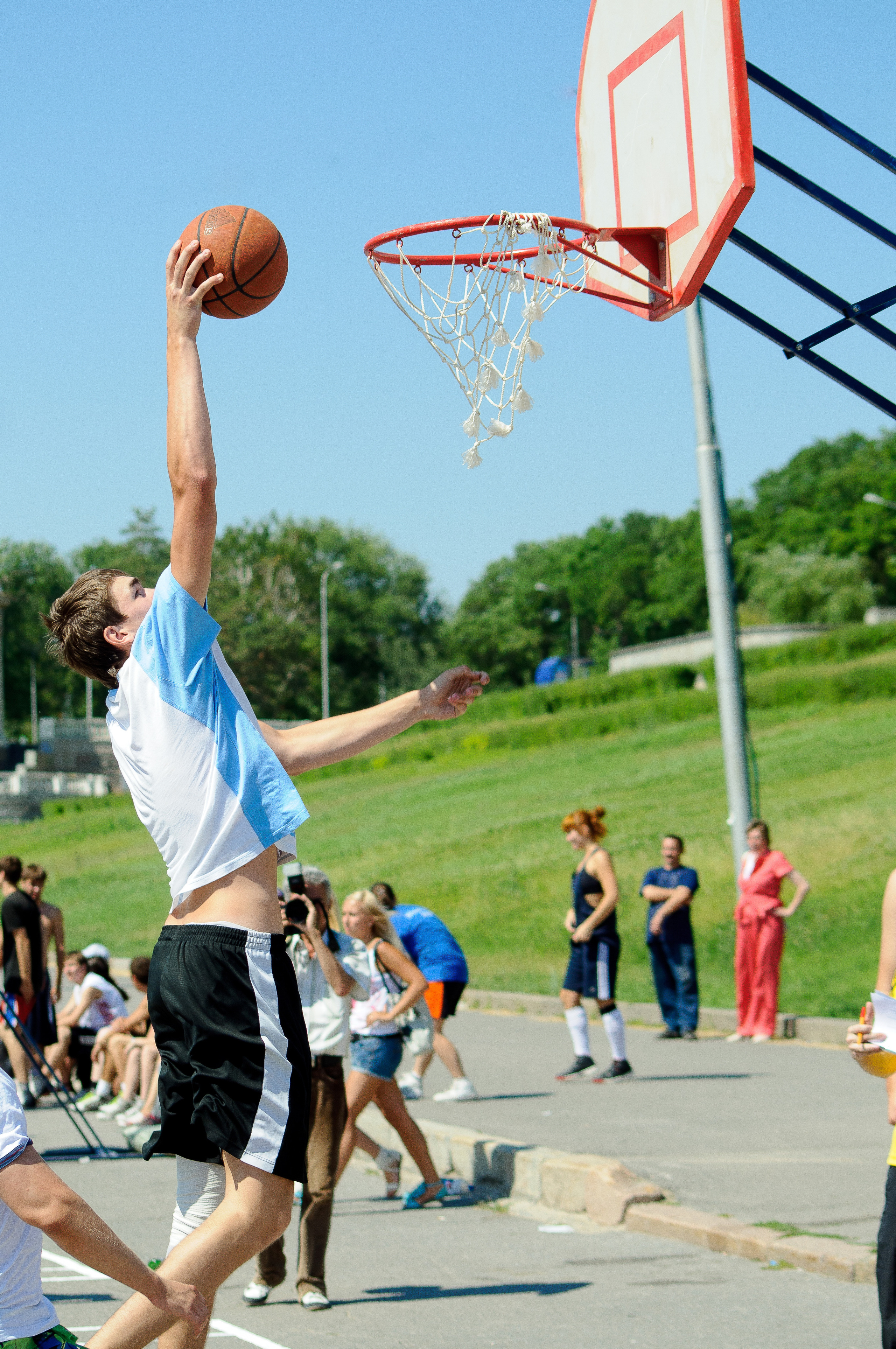 Баскетболист на соревнованиях в полёте забрасывает мяч в кольцо