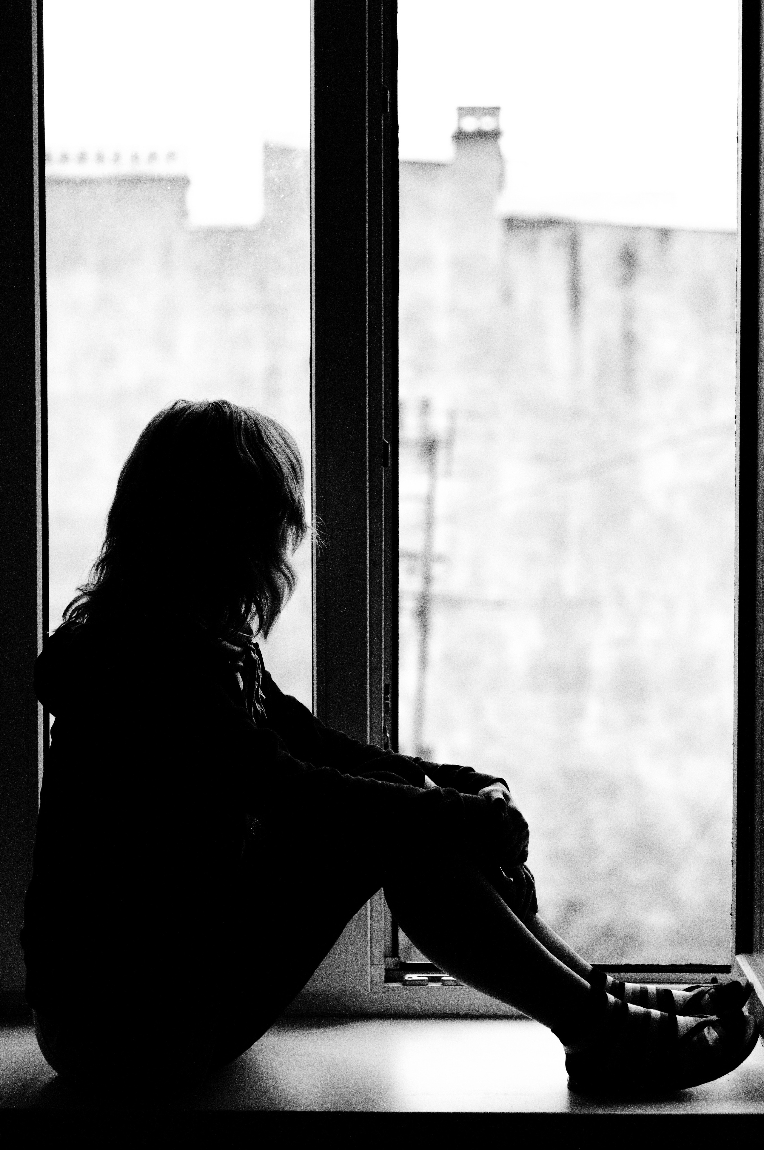 Девушка сидит на подоконнике высокого окна 