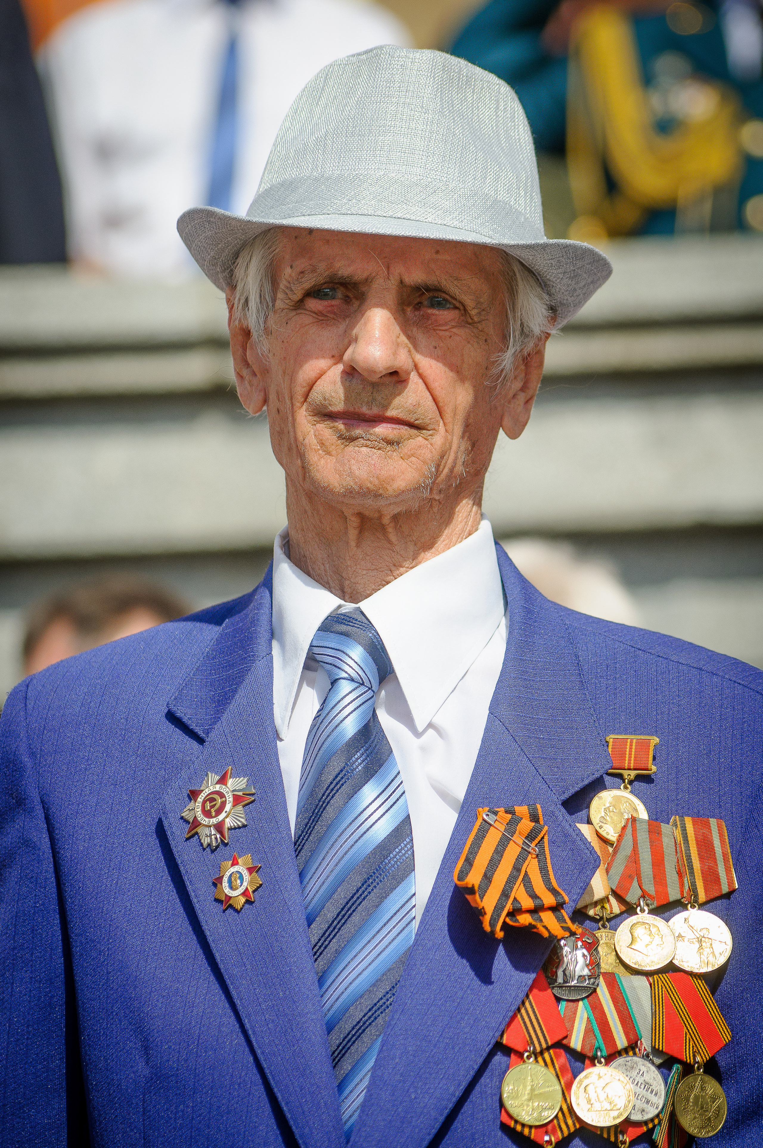 Ветеран с медалями в синем костюме и белой шляпе