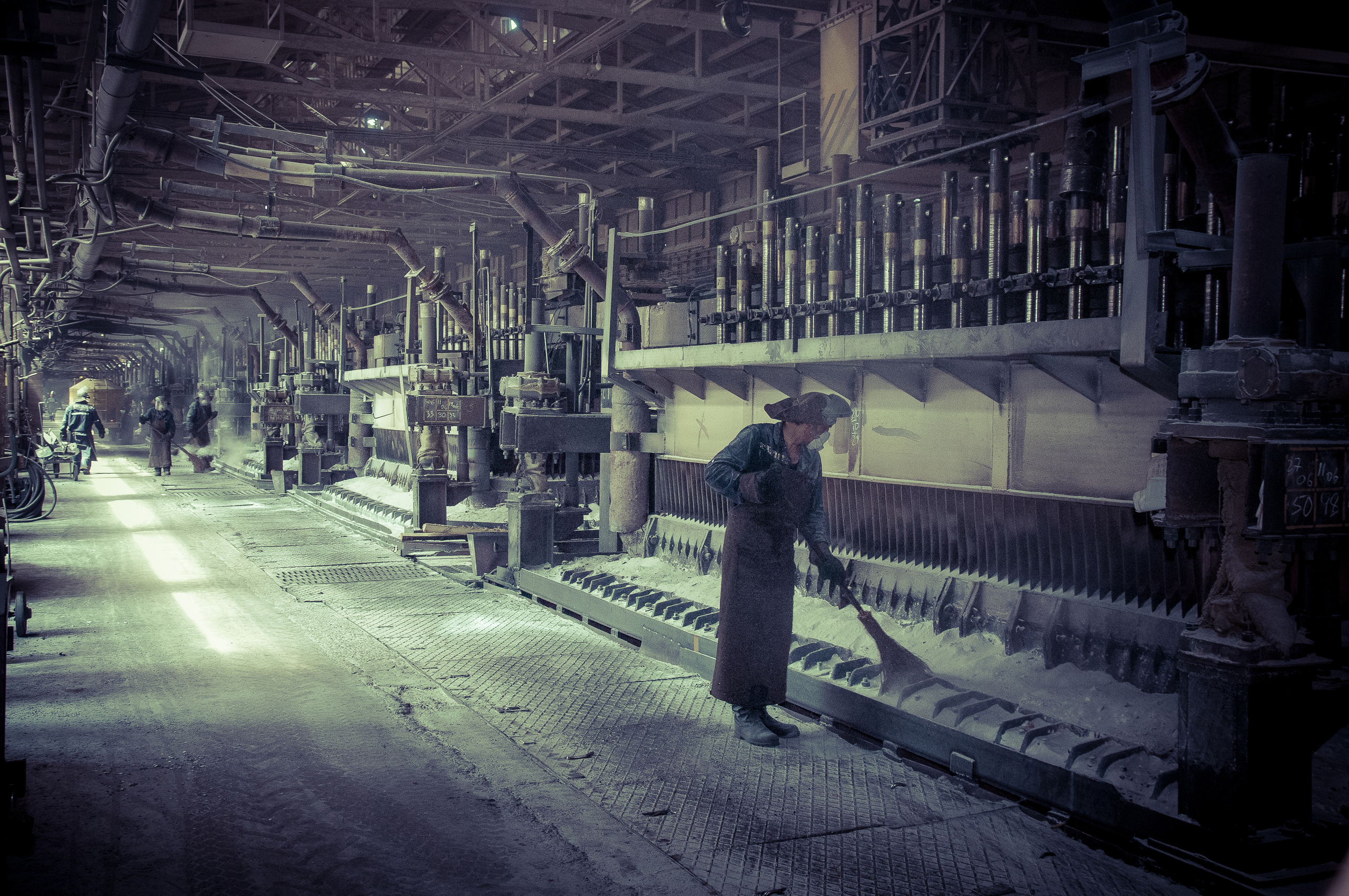 Уборщик убирает отходы около печей алюминиевого завода