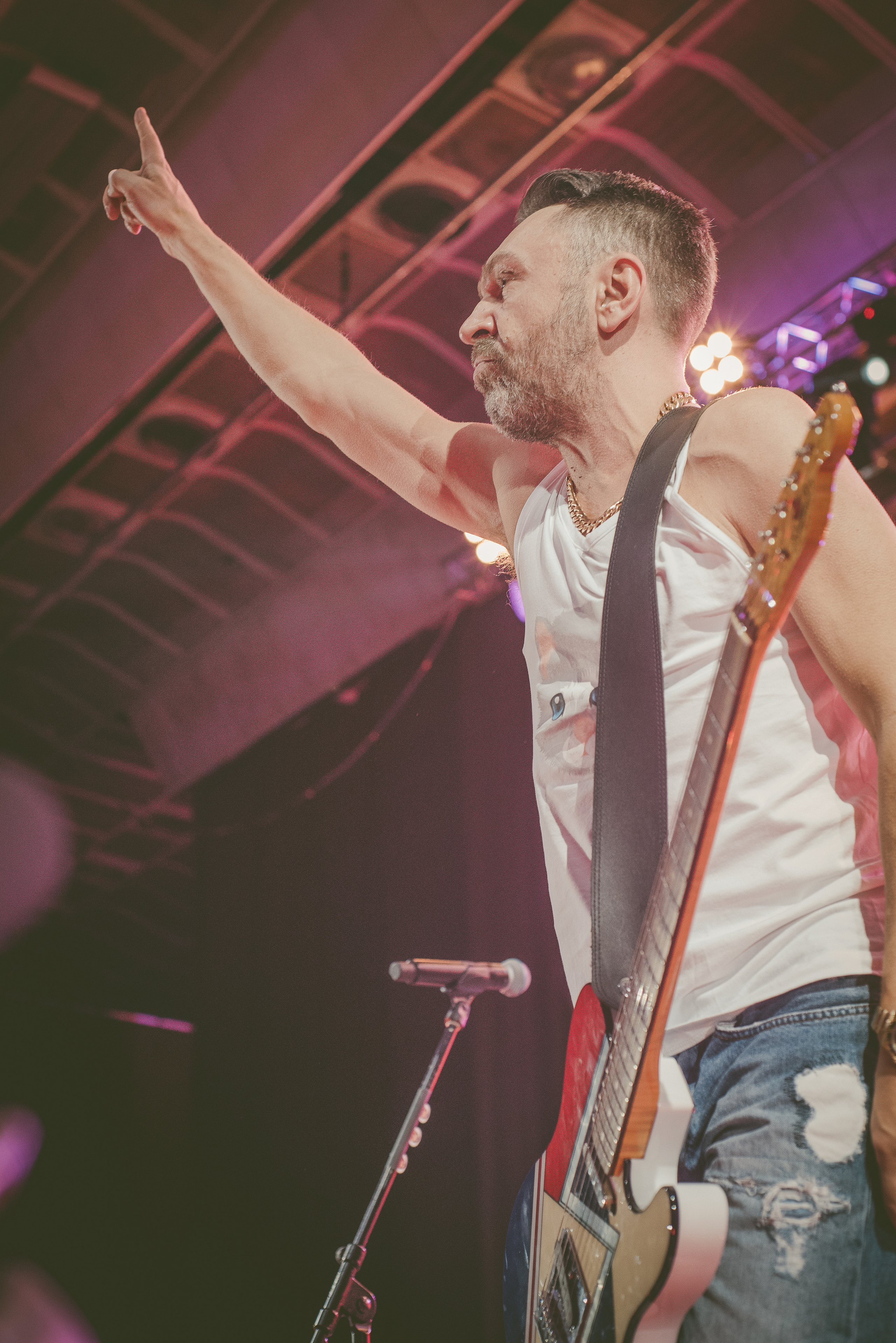 Сергей Шнуров на концерте группы Ленинград стоит с гитарой и поднятой рукой