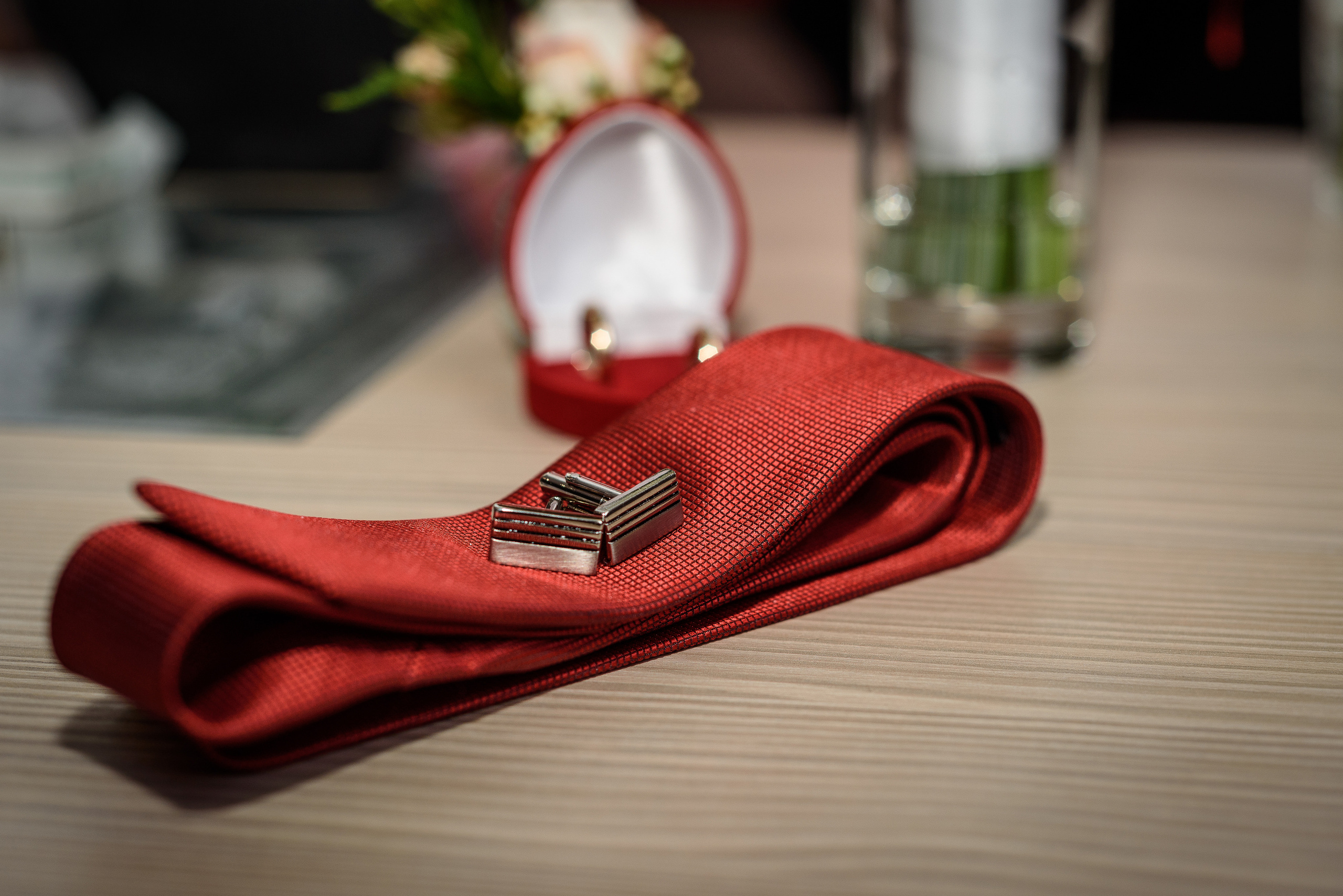 Запонки и красный галстук жениха лежат на столе