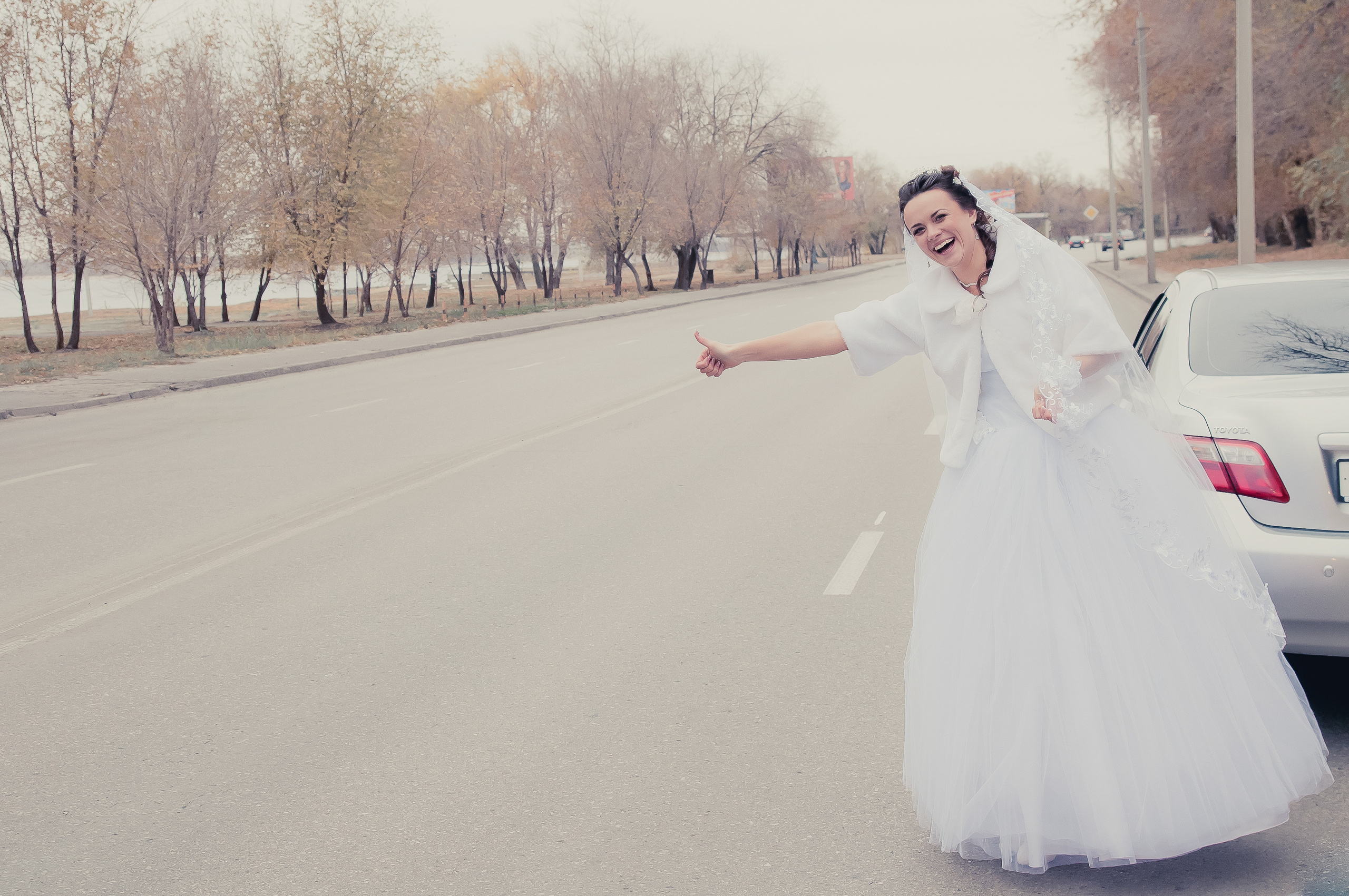 Невеста на дороге делает жест автостопщиков