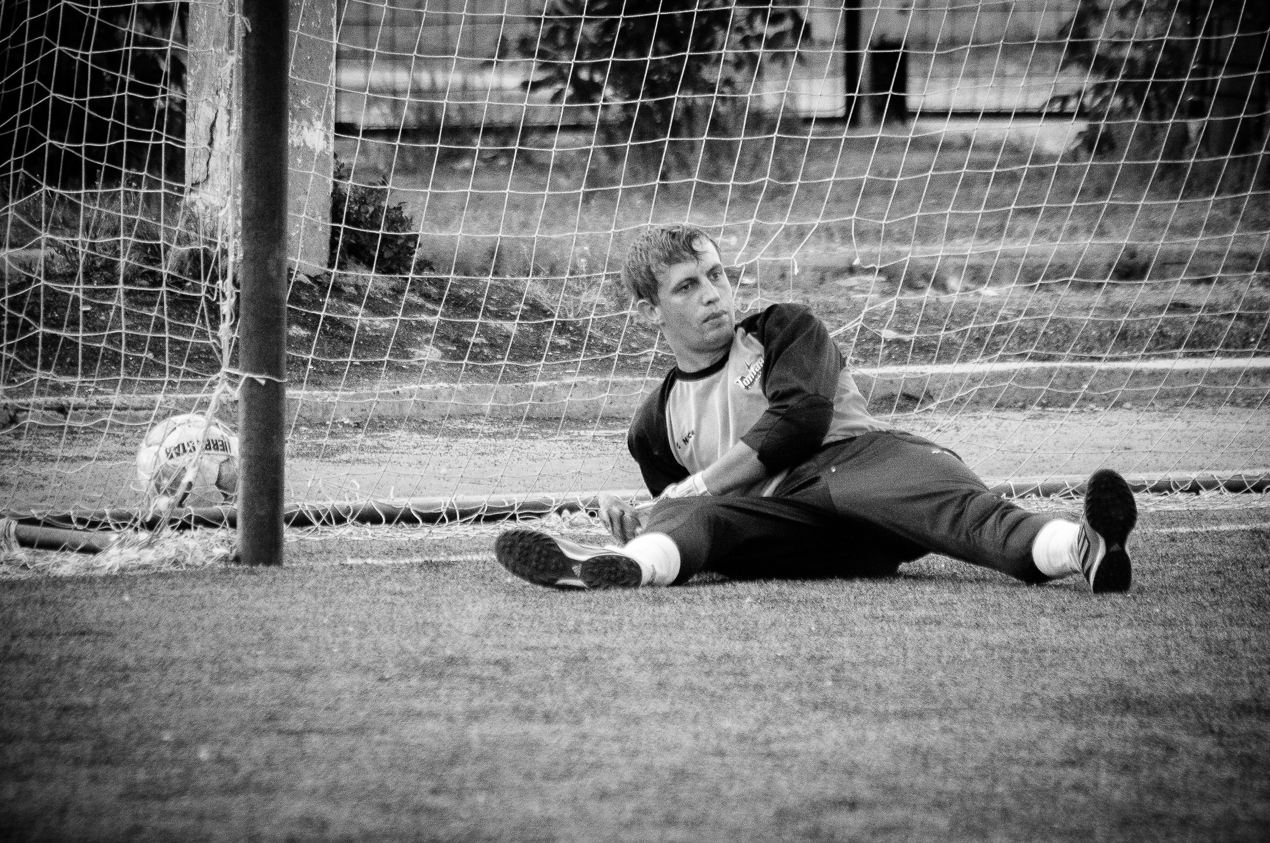 Футбольный вратарь лежит на земле после пропущенного гола