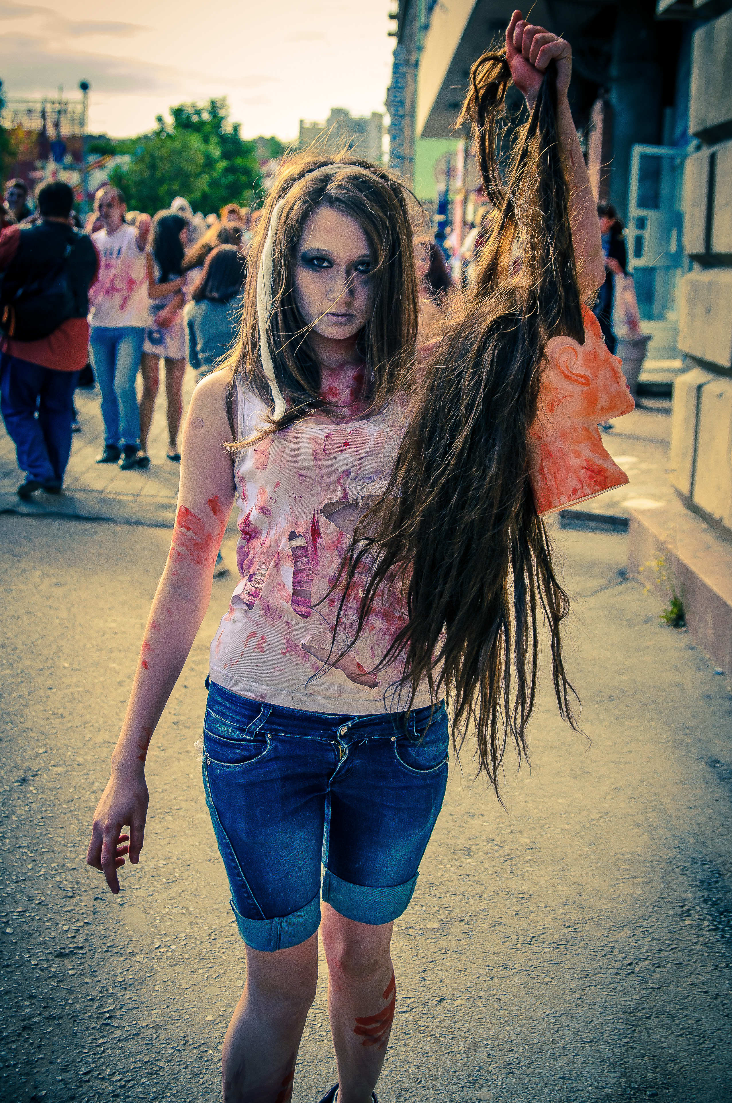 Девушка-зомби держит за волосы голову манекена