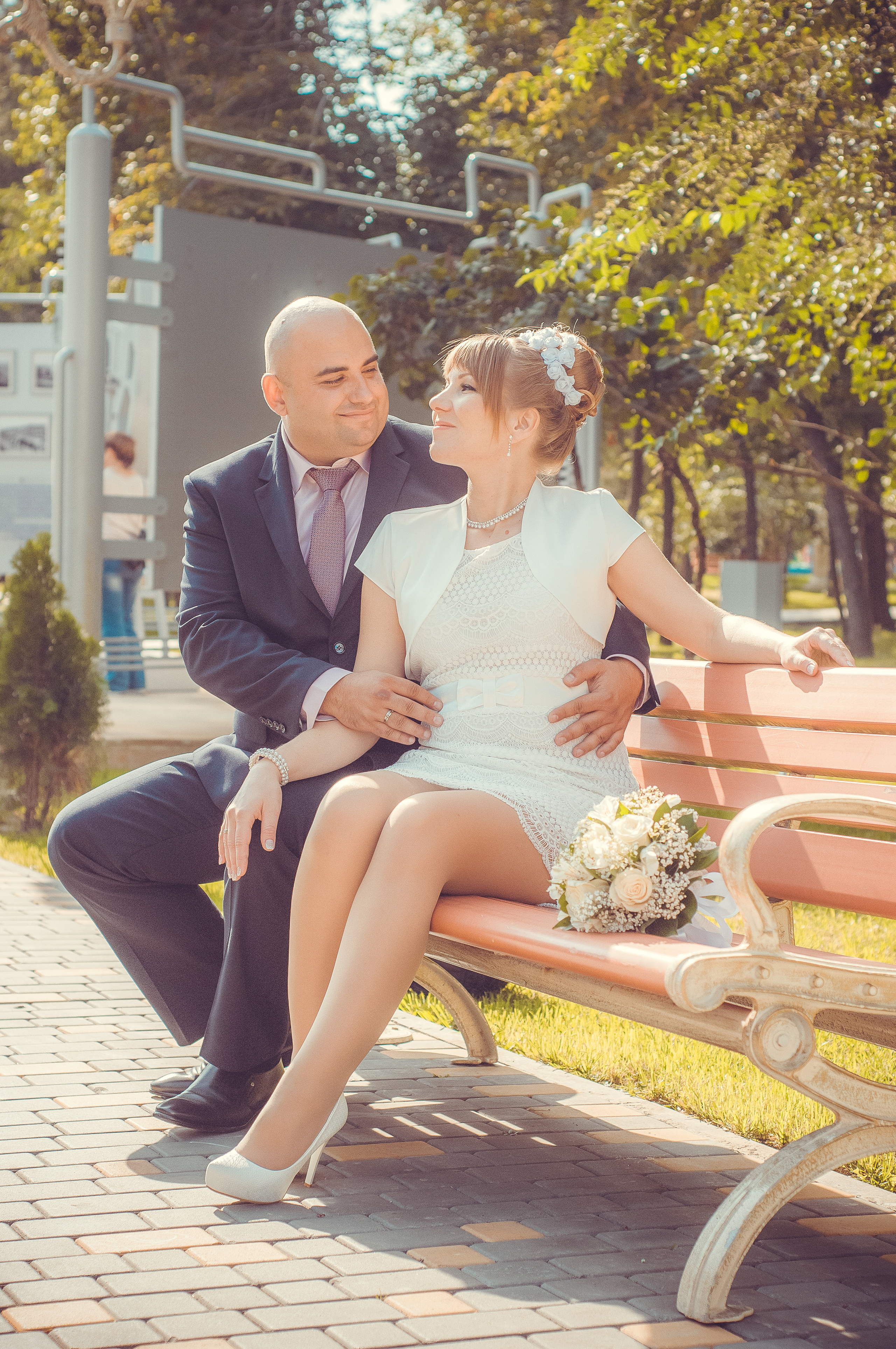 Жених и невеста сидят на скамье в парке