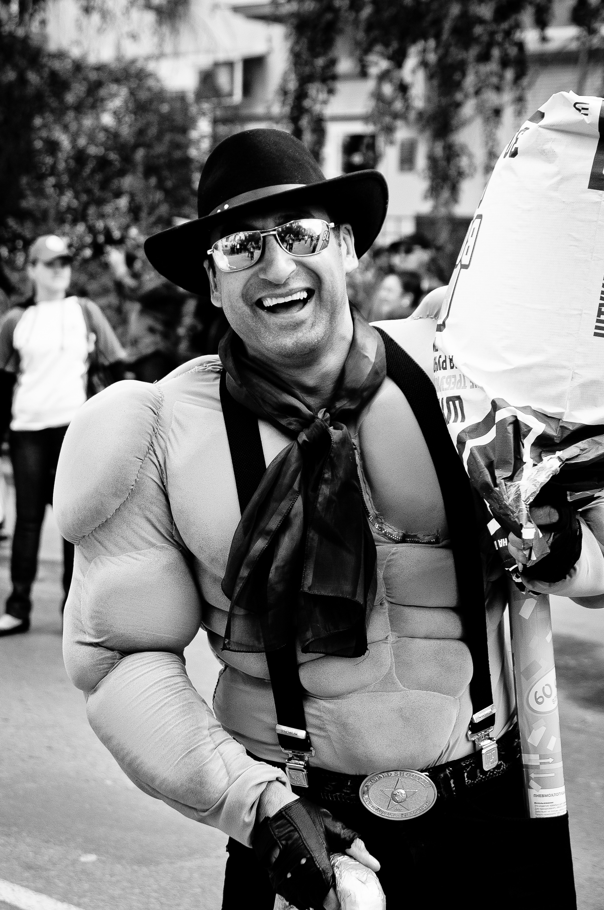 Мужчина в костюме силача, в ковбойской шляпе и очках