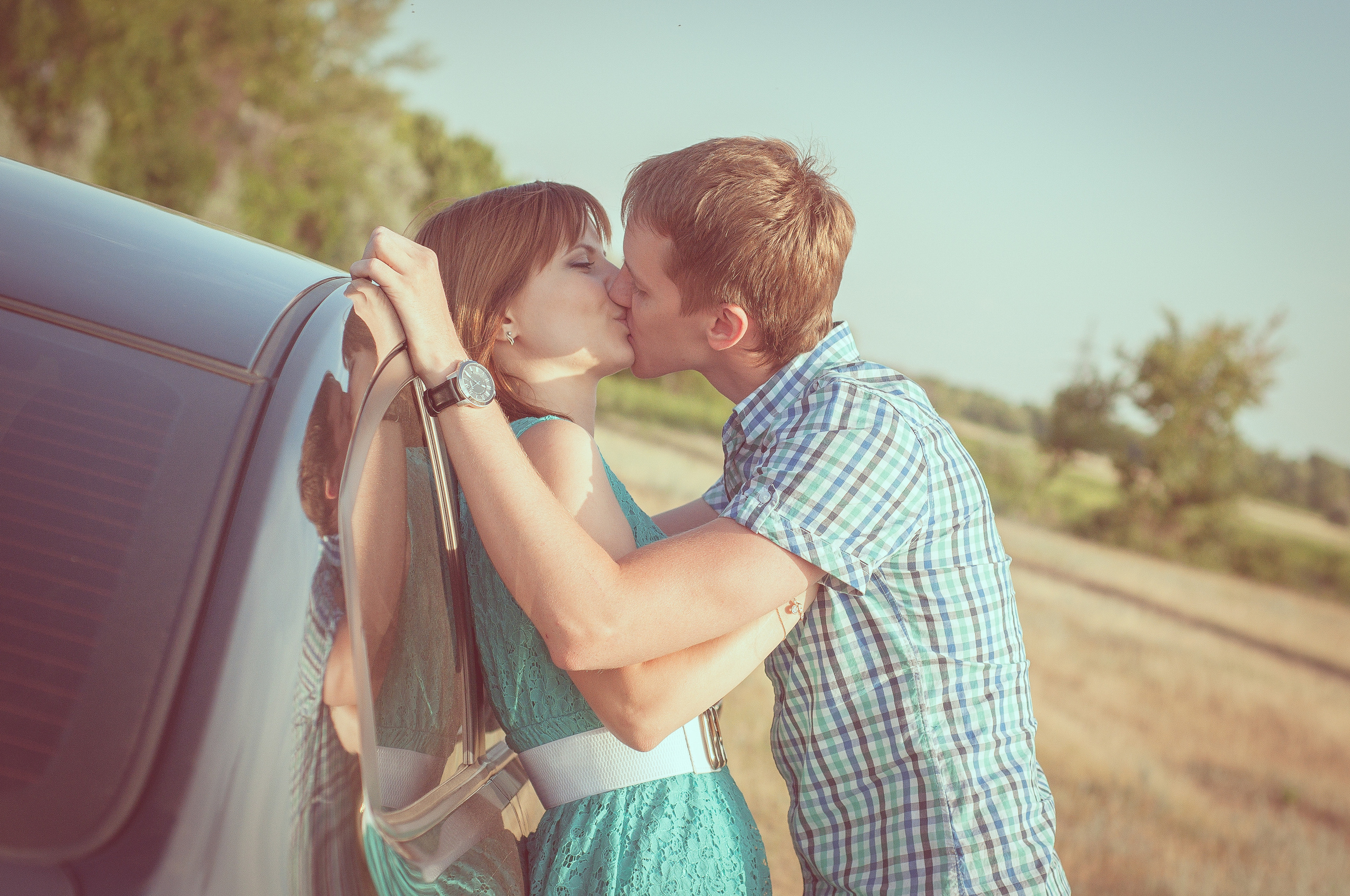 Парень и девушка целуются стоя около автомобиля