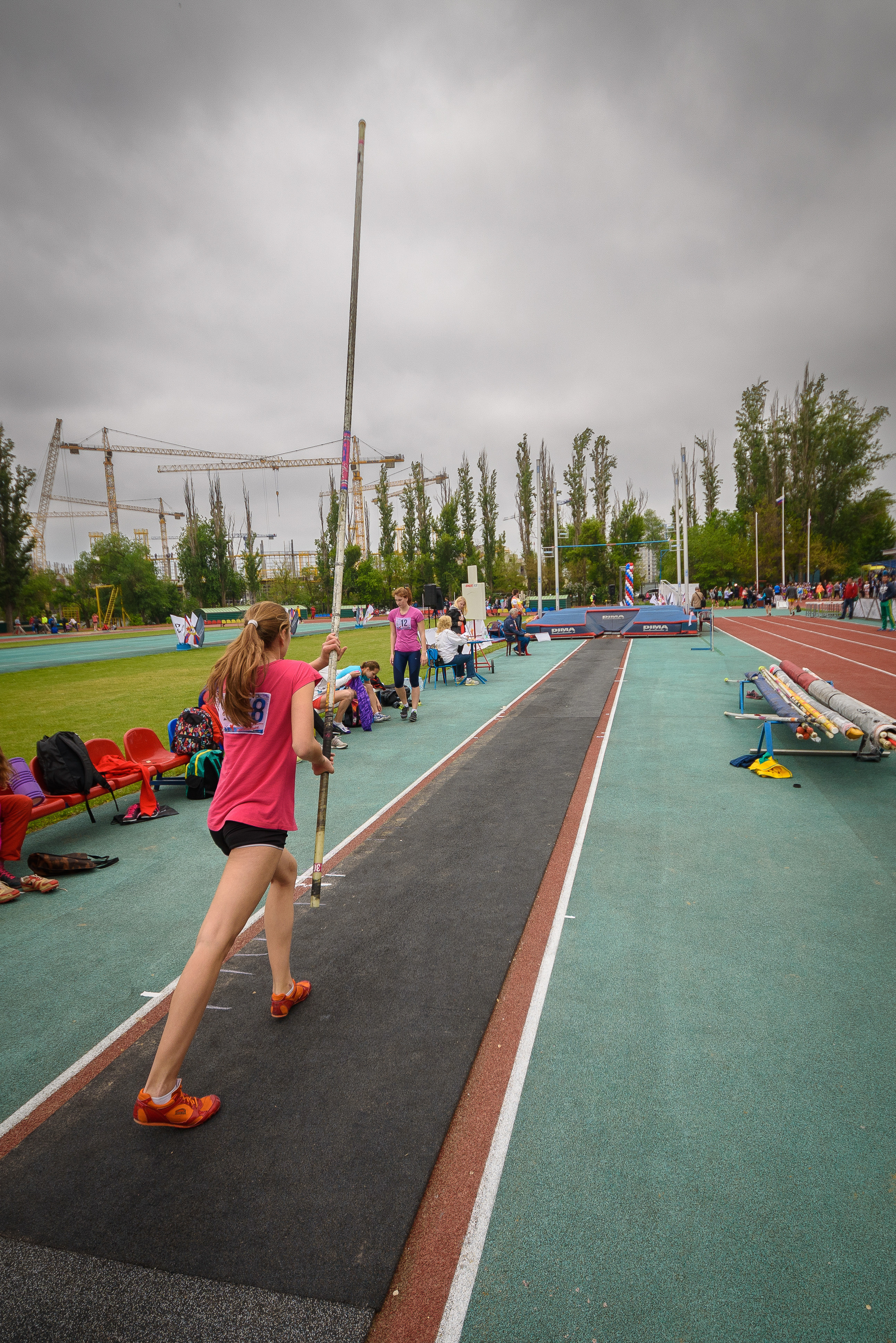 Спортсменка на стадионе готовится совершить прыжок с шестом