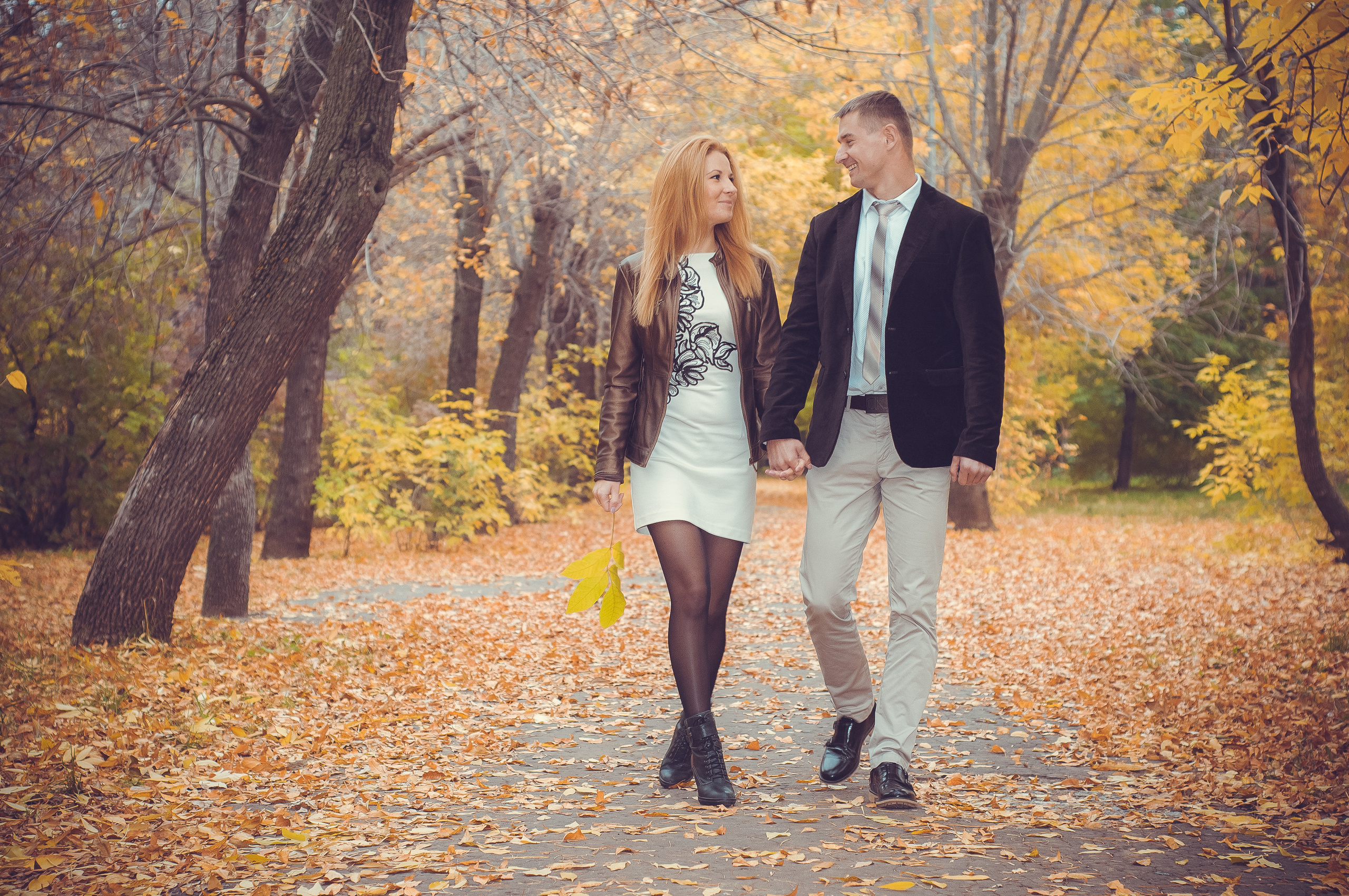 Влюблённая пара идут по осеннему парку и смотрят друг на друга