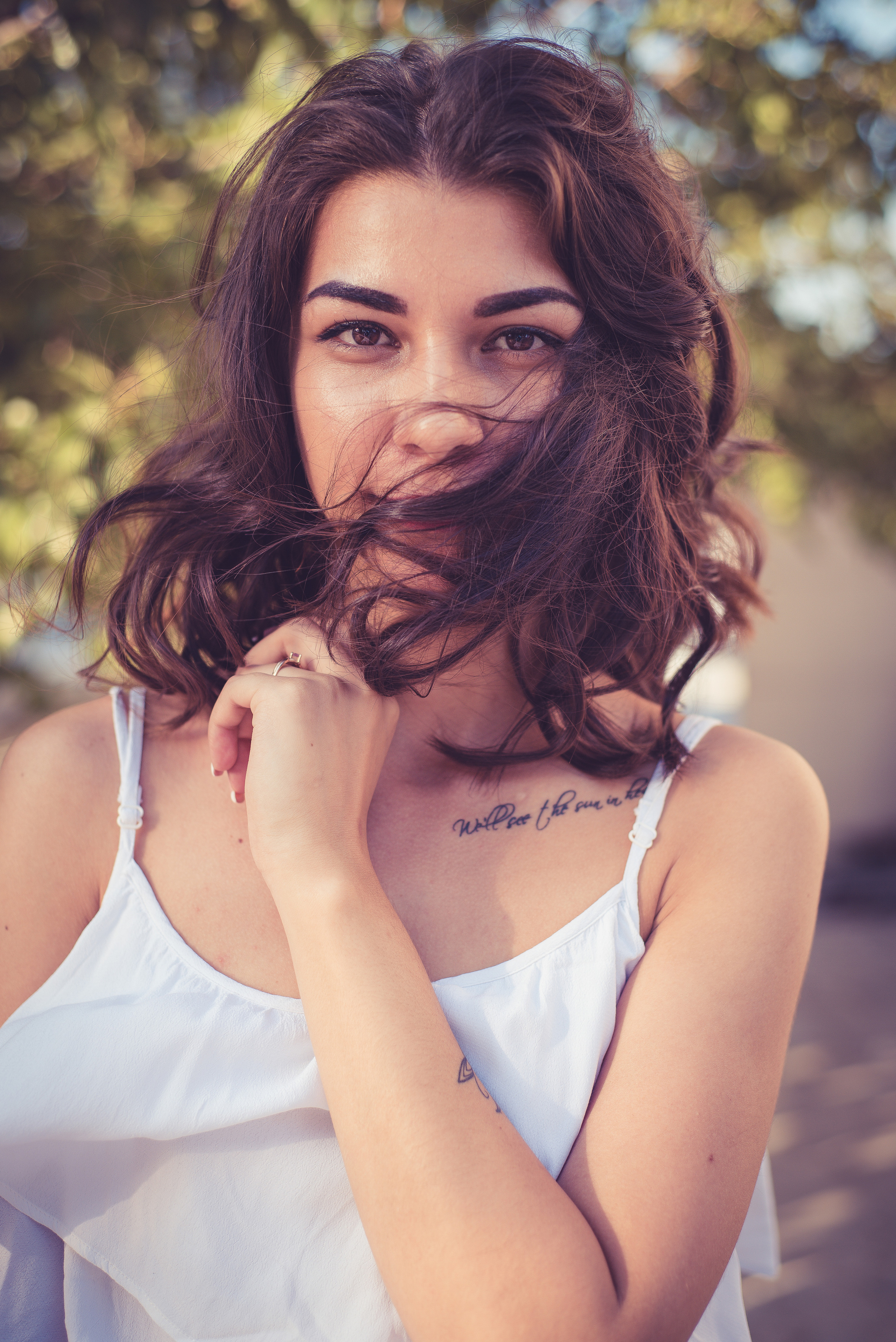 Девушка в белой майке держит свои волосы