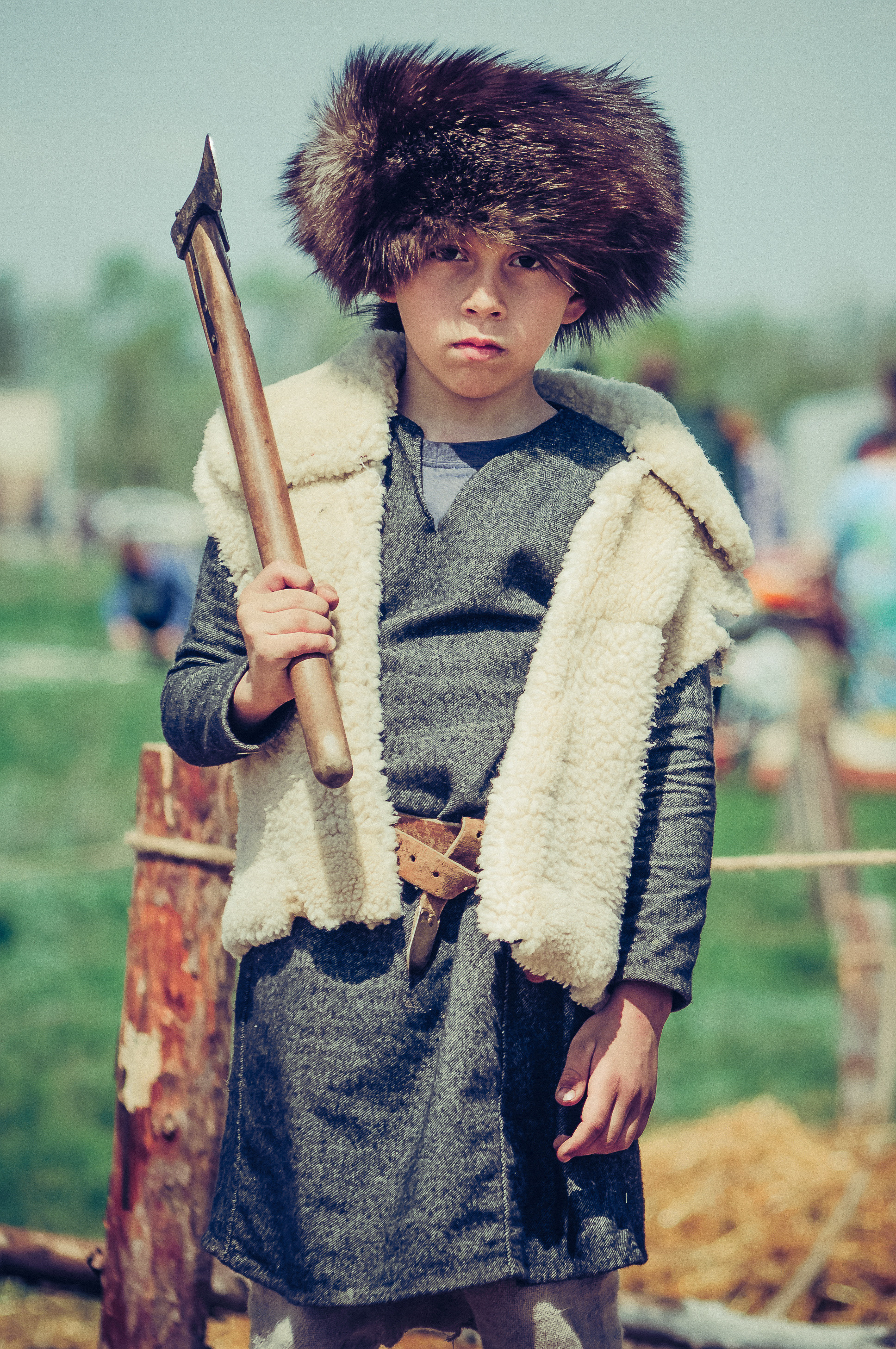 Мальчик в историческом костюме с папахой на голове держит топор на плече
