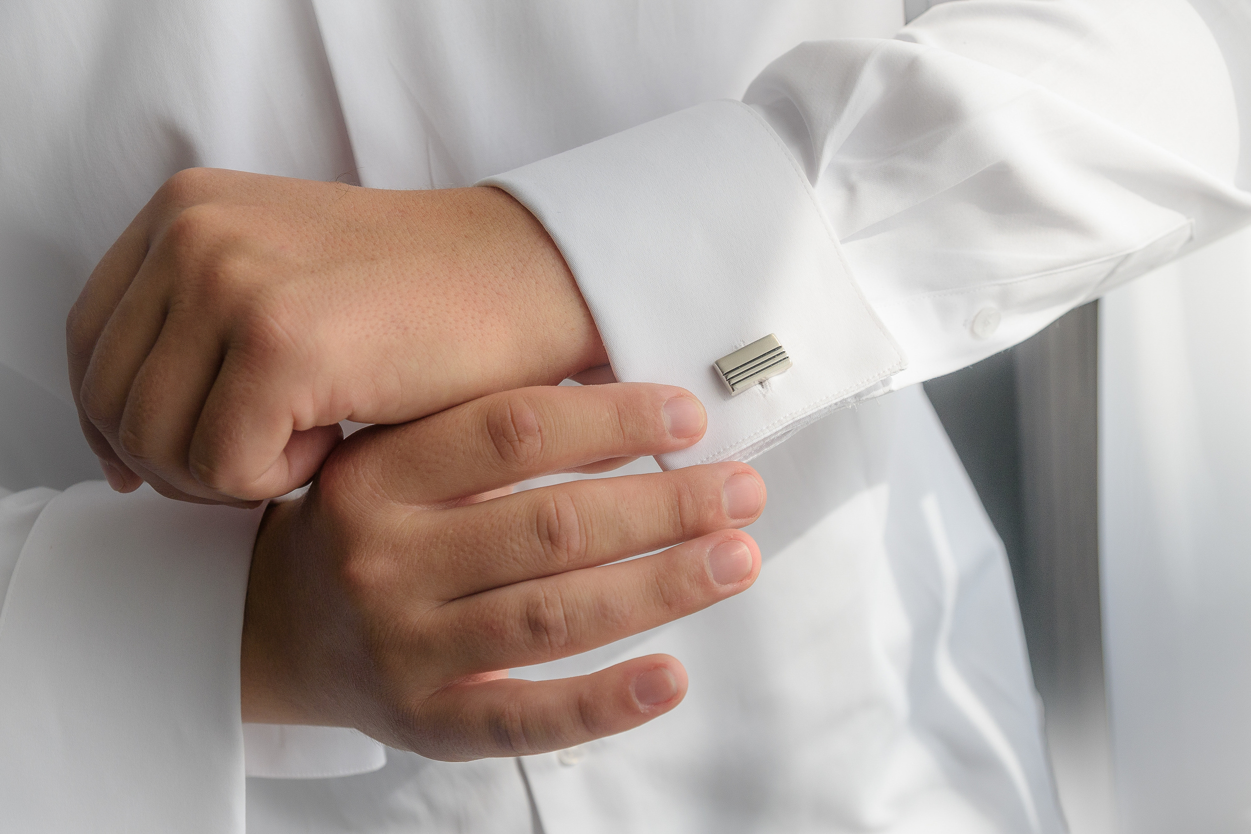 Жених поправляет запонку на белой рубашке