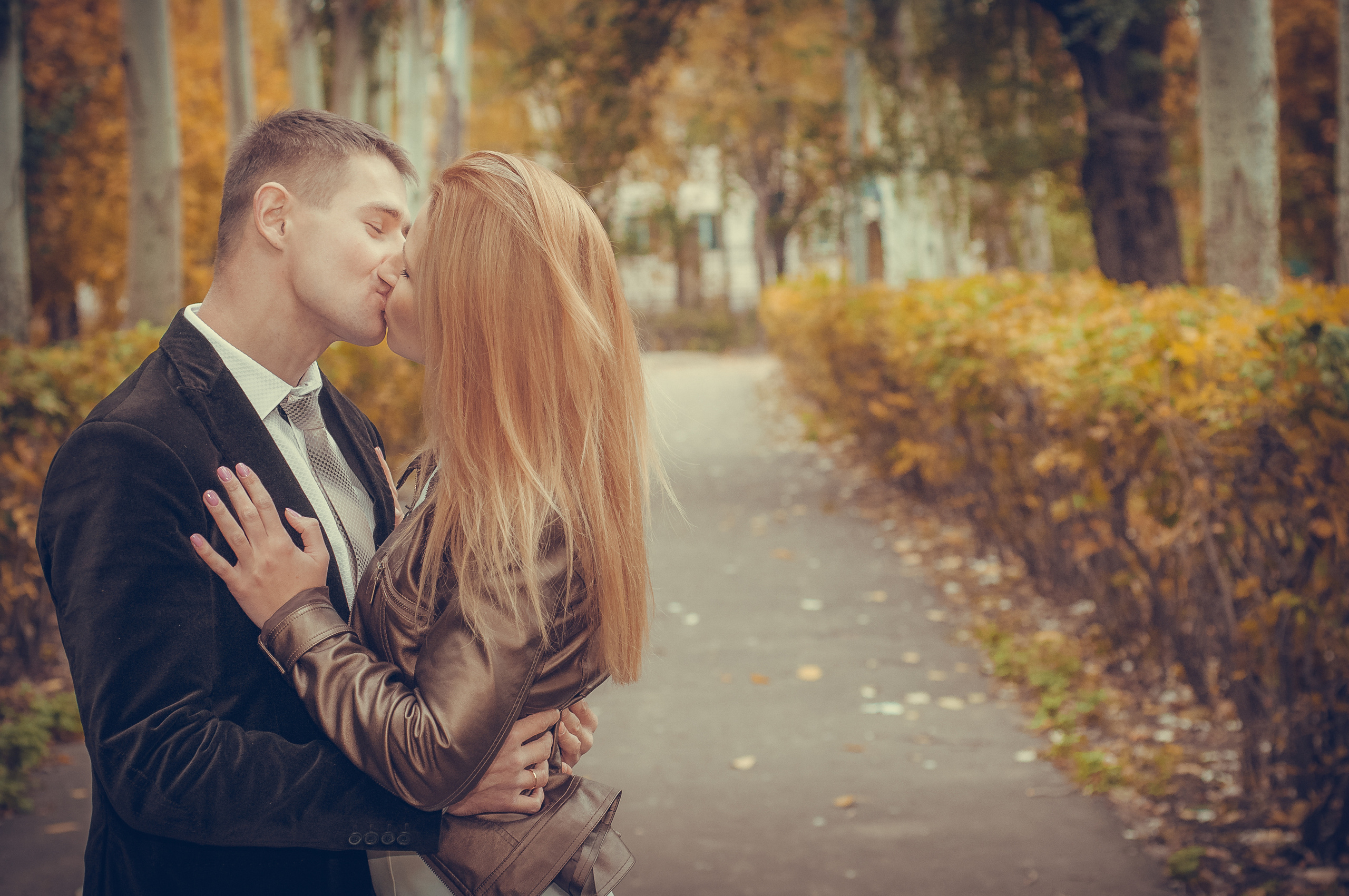 Парень и девушка целуются в осеннем парке