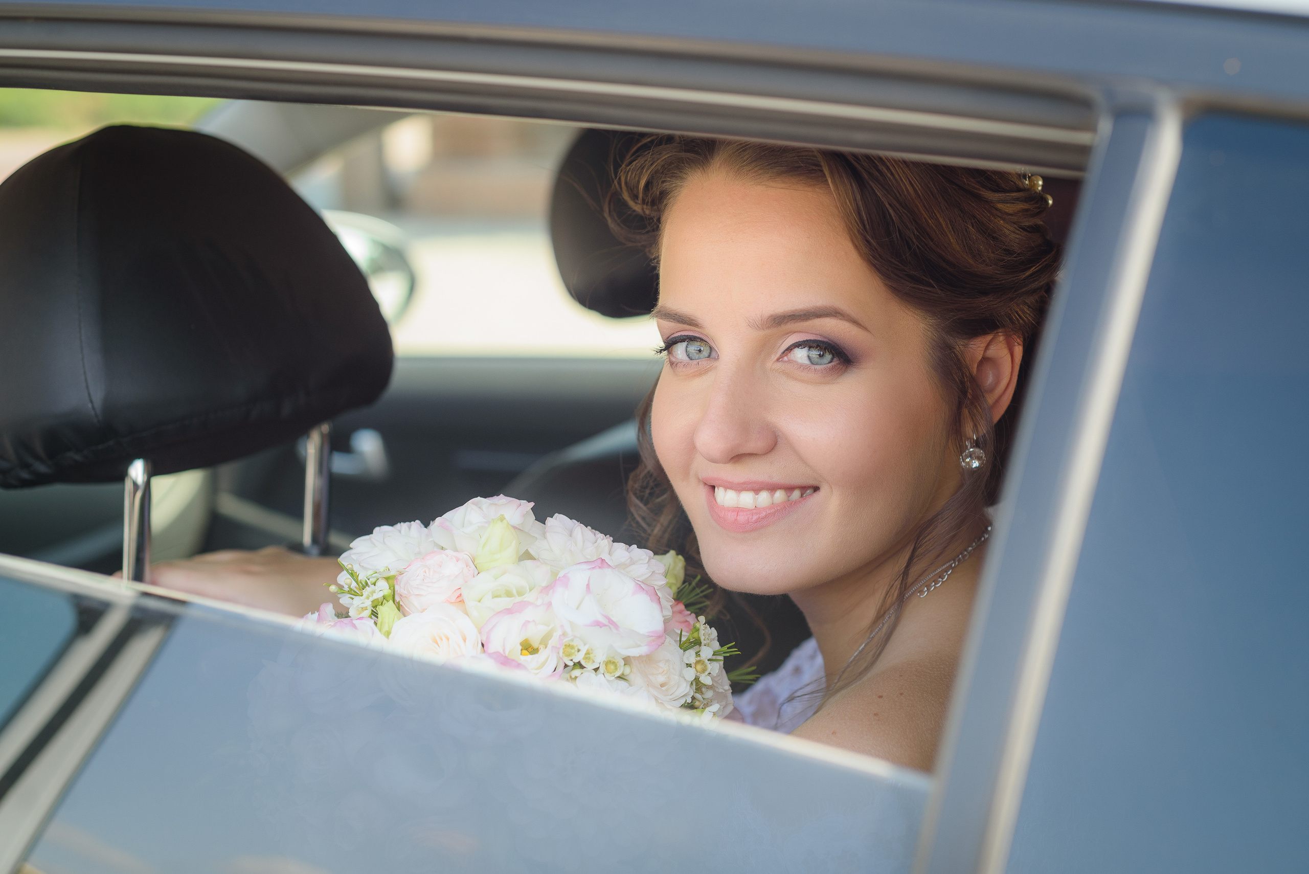 Невеста с букетом смотрит из открытого окна автомобиля
