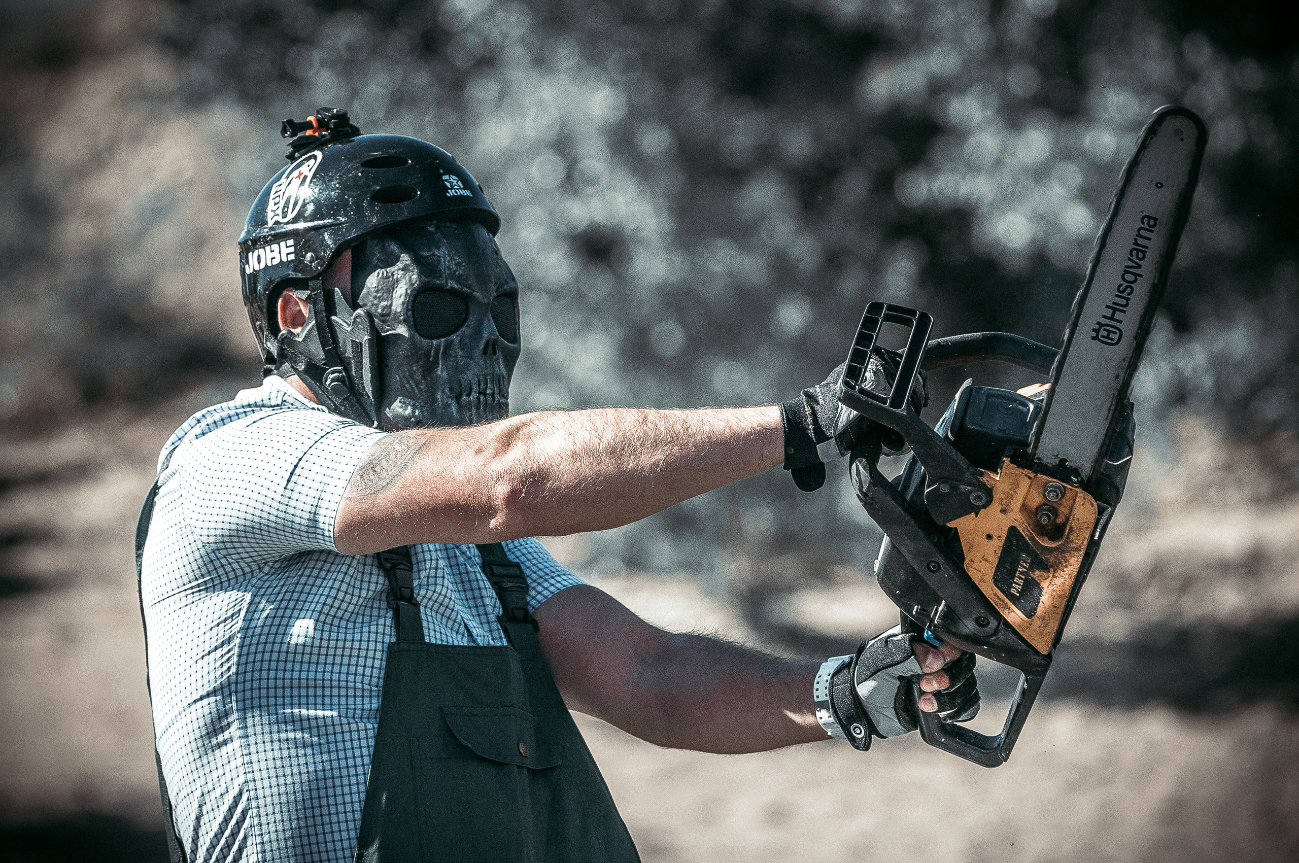 Мужчина в маске маньяка с бензопилой в руках