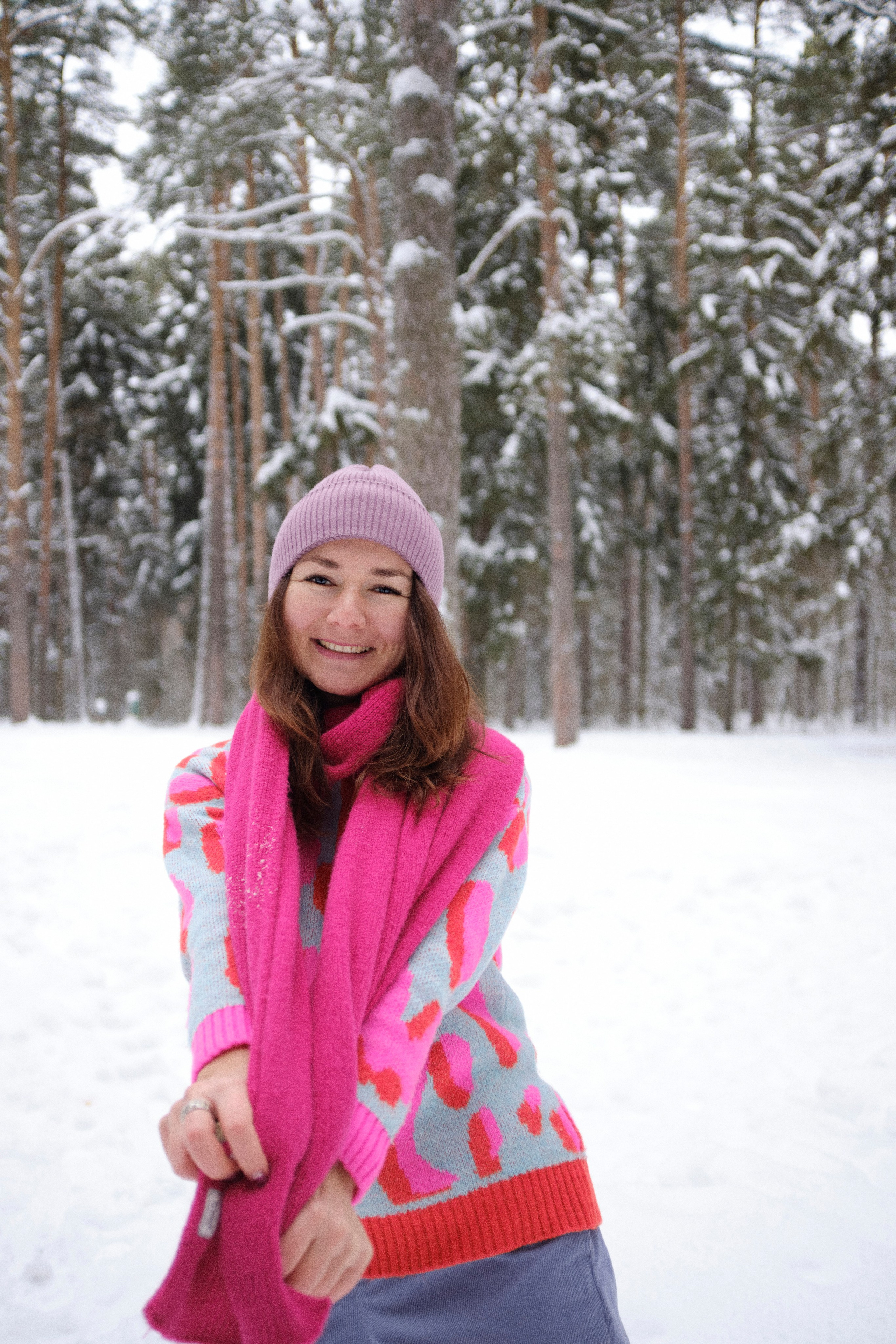 Женщина в яркой одежде и уютном шарфе в снежном лесу