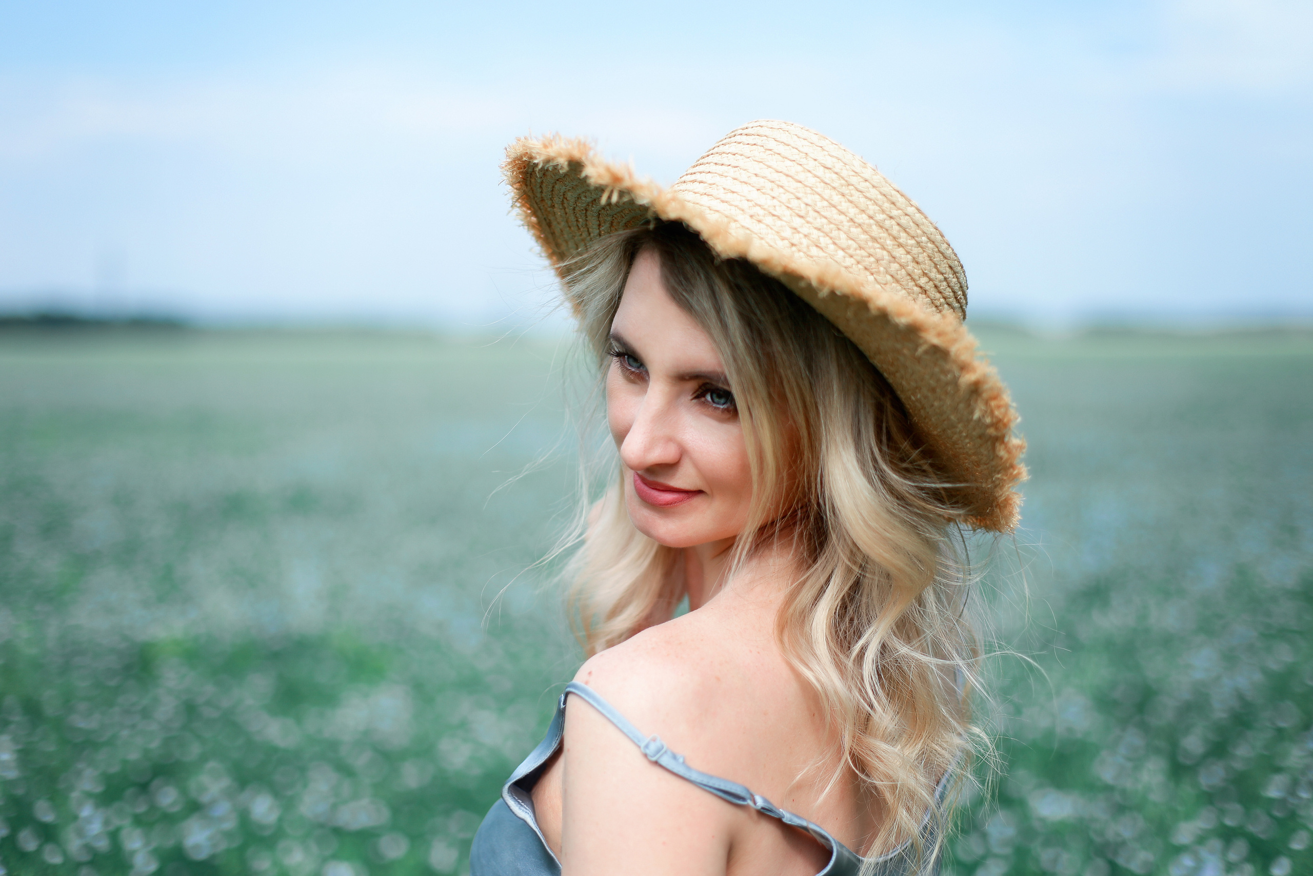 Женский портрет в соломенной шляпке, со спущенной лямкой платья в поле.