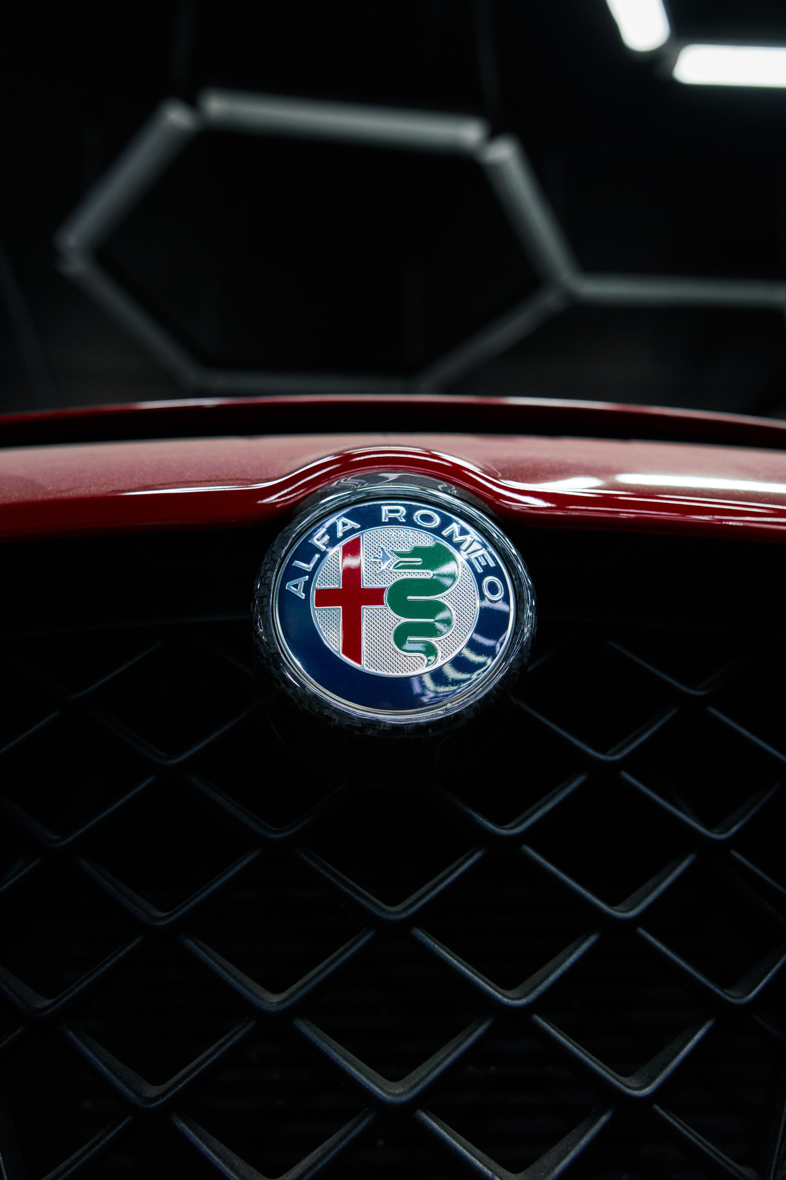Крупный план значка Alfa Romeo на решетке радиатора, автомобильные детали от GLAR Production