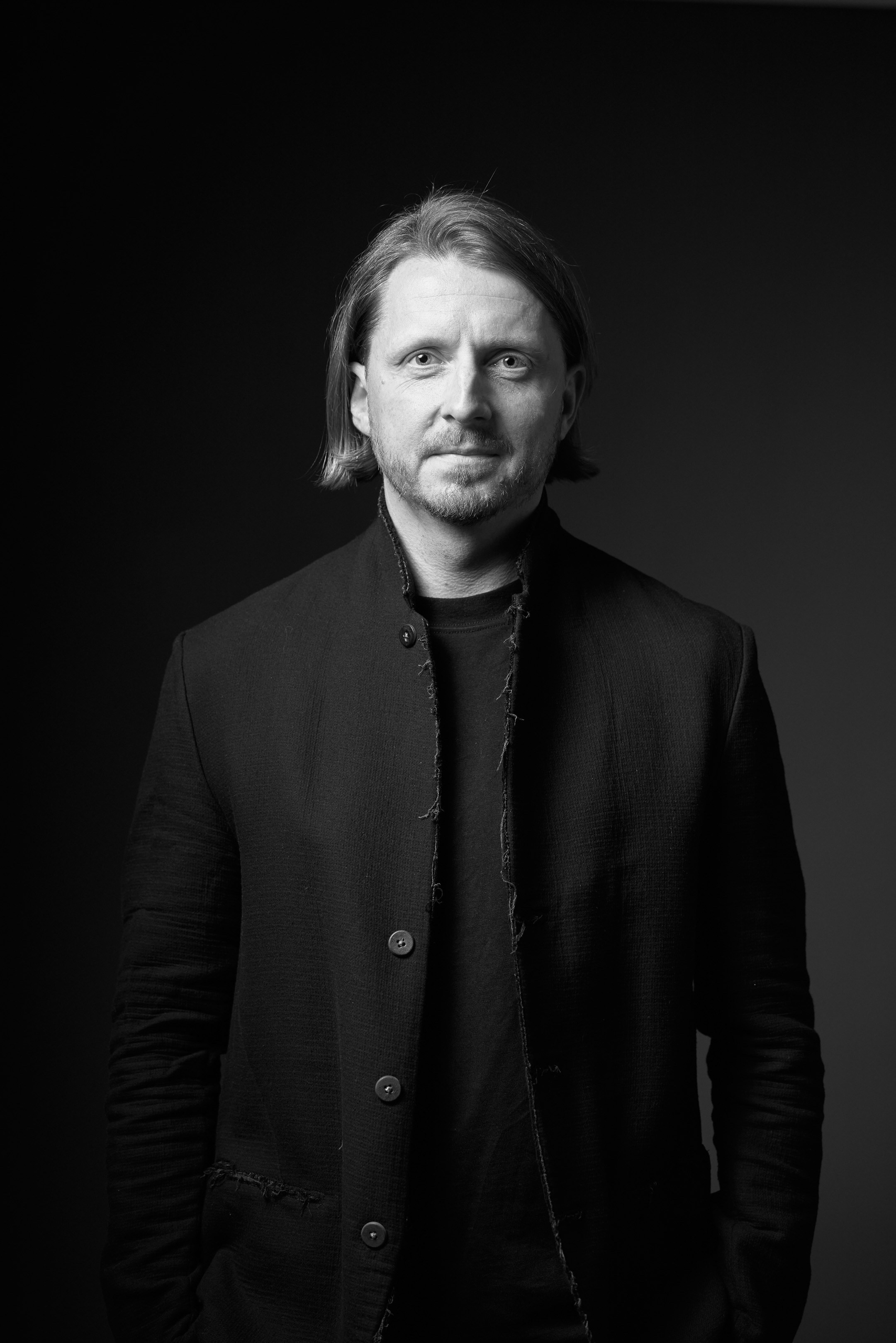 Black and white business portrait of a confident man in a suit on a black background