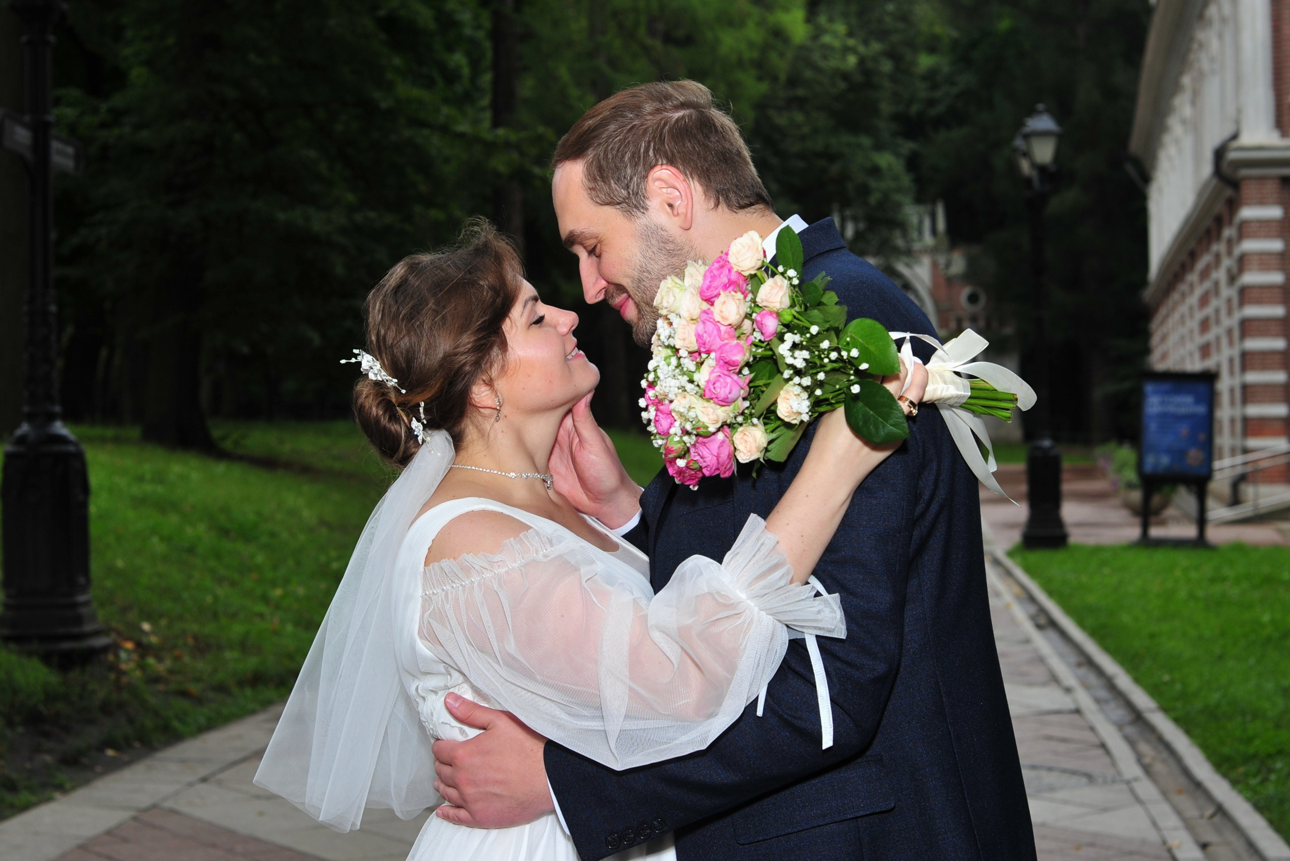 Свадьба в Царицыно пасмурным летним днем, жених и невеста обнимаются и смотрят друг на друга в темном парке перед дождем 