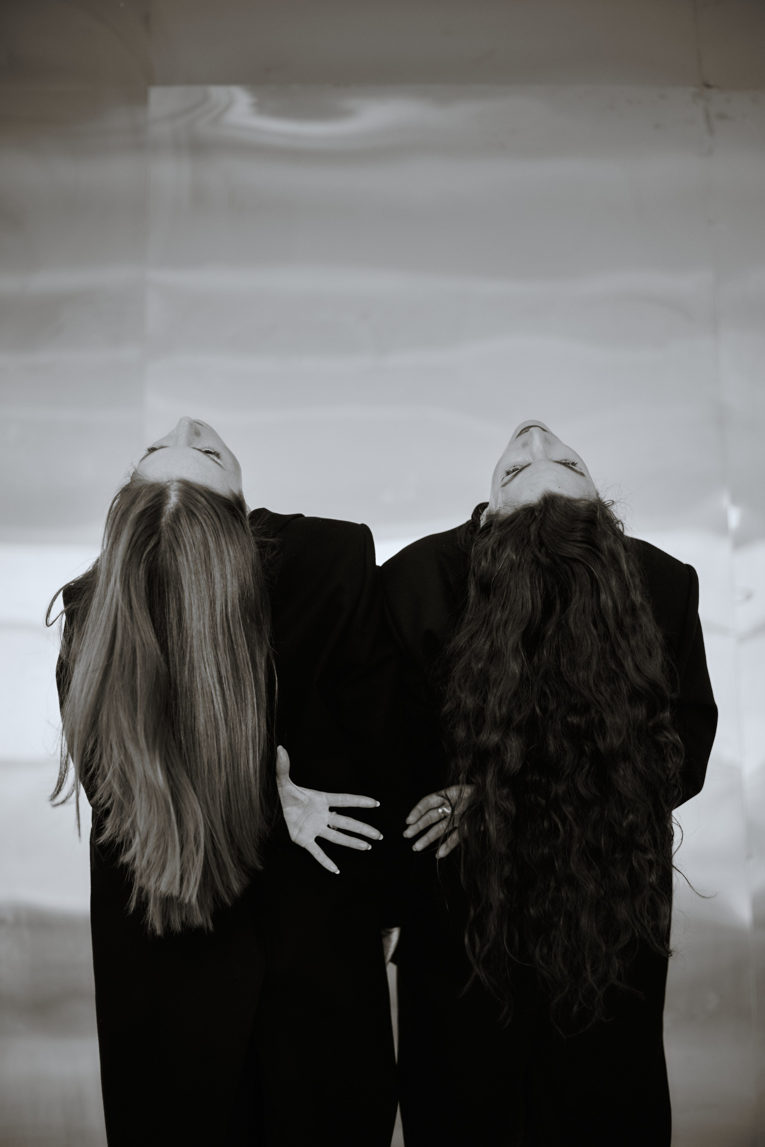 Две девушки на фоне металлической стены, стоят спиной с запрокинутой головой, взявшись за руки. Виктория Брызгалова и Анна Пижонкова