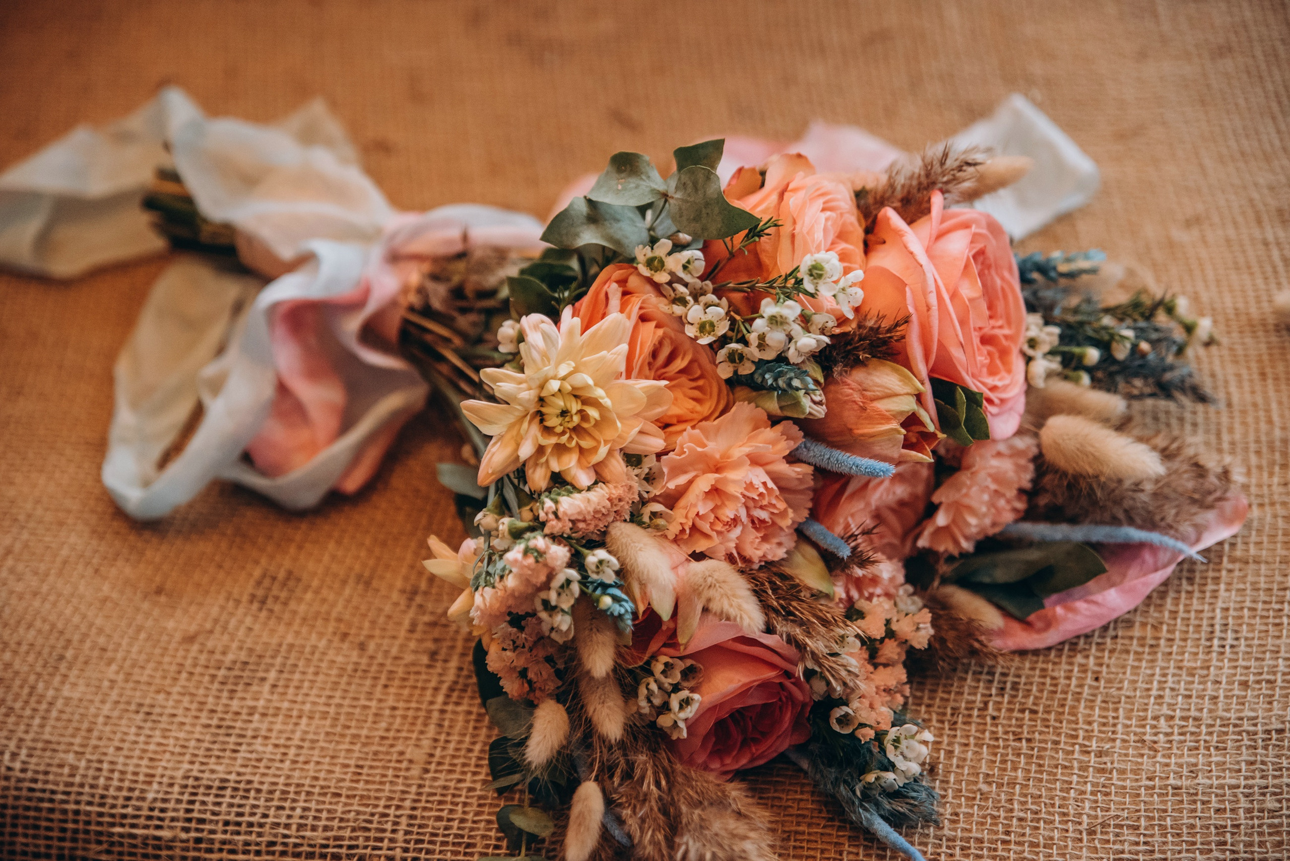 Букет невесты, перевязанный белой лентой, лежит на кровати