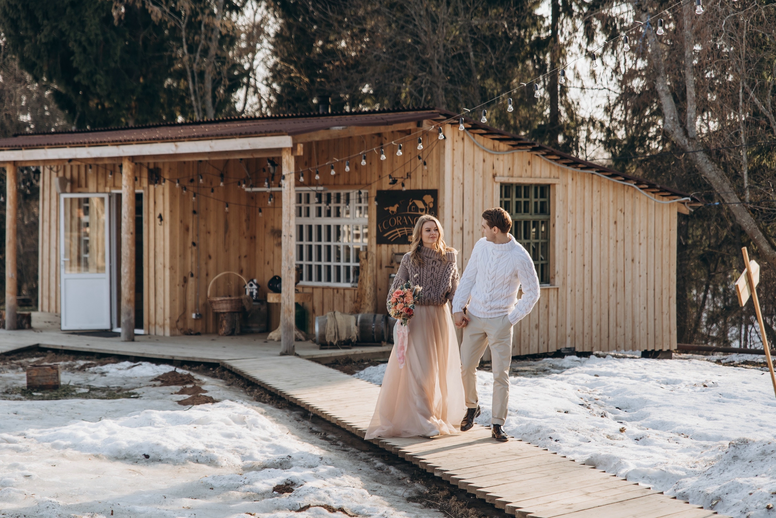 Жених и невеста на фотосессии зимой гуляют по территории отеля.