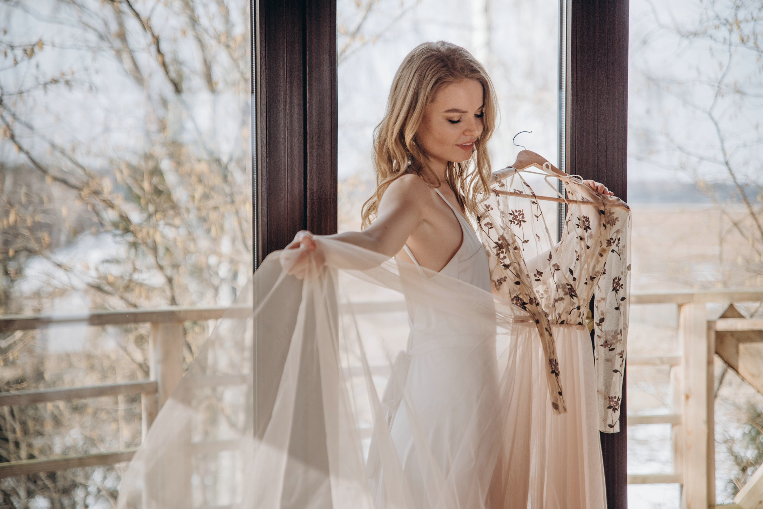 Невеста примеряет свадебное платье ранним утром в отеле.