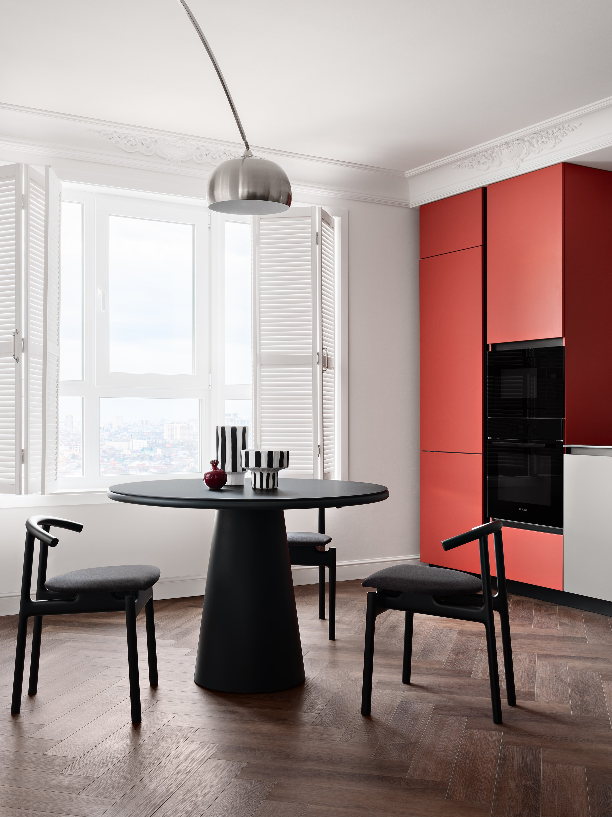 Элегантная обеденная зона с круглым черным столом, стильными стульями и панорамными окнами с белыми ставнями, создающая уют и свет. Дизайн Антона Логинова, стилистика Алёны Мощенской, фото Сергея Денисенко.