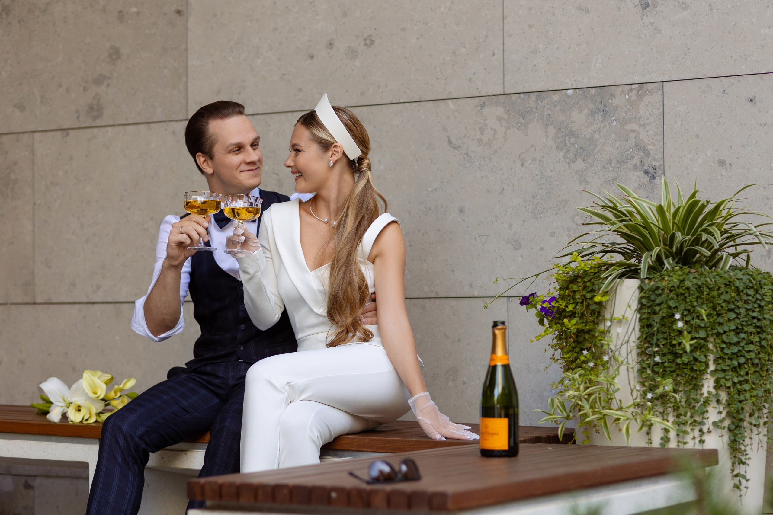 Молодожены чокаются бокалами с шампанским.
