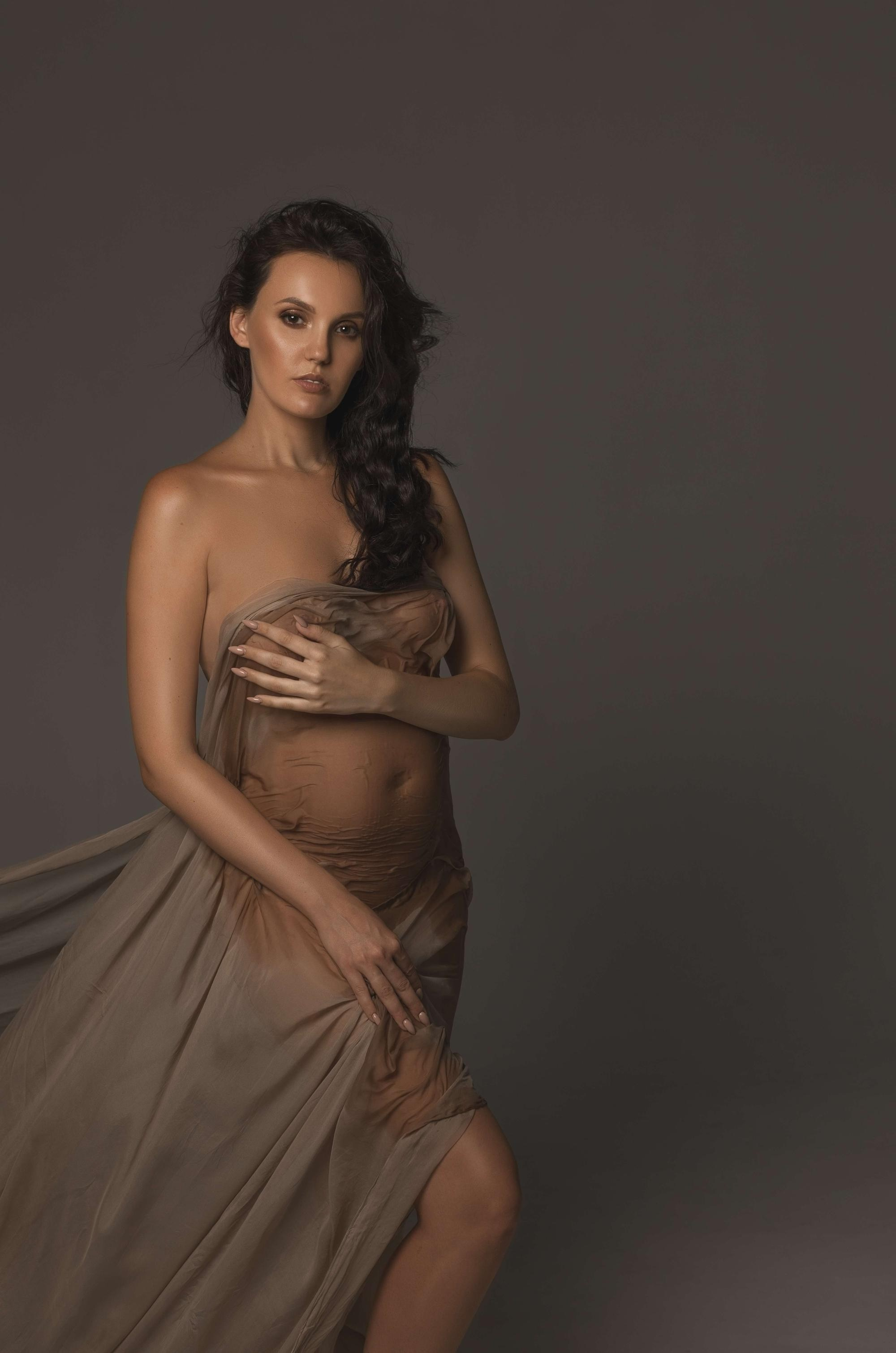 фотосессия беременной в фотостудии на темном фоне в красивом разлетающемся платье, фотография беременности, фотосессия беременных, портрет беременной