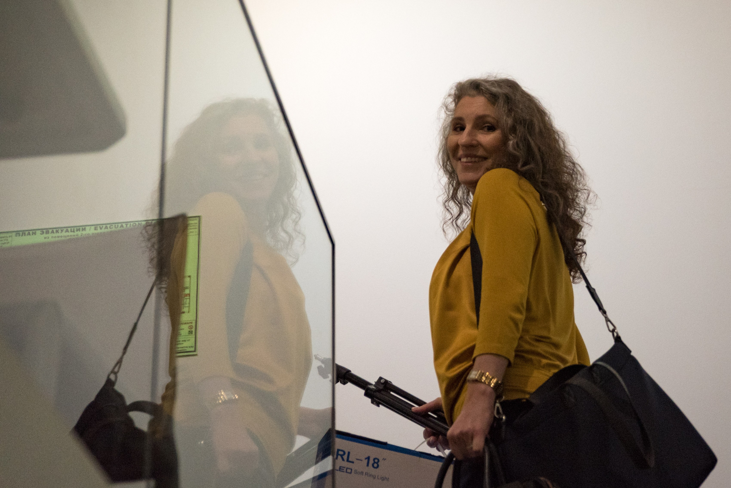 Женщина поднимается по лестнице, отражается в стекле.