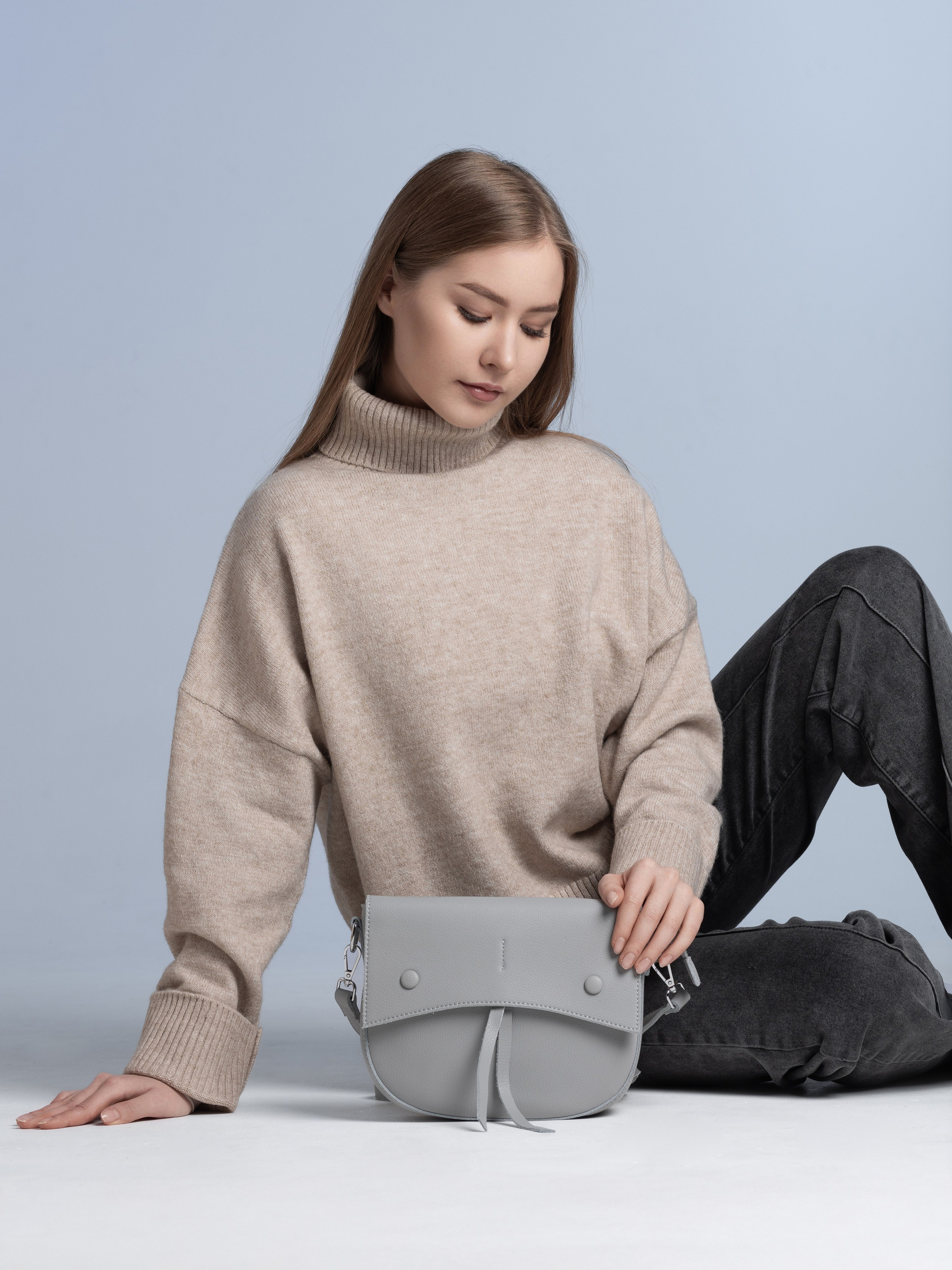 Девушка демонстрирует серую женскую сумочку