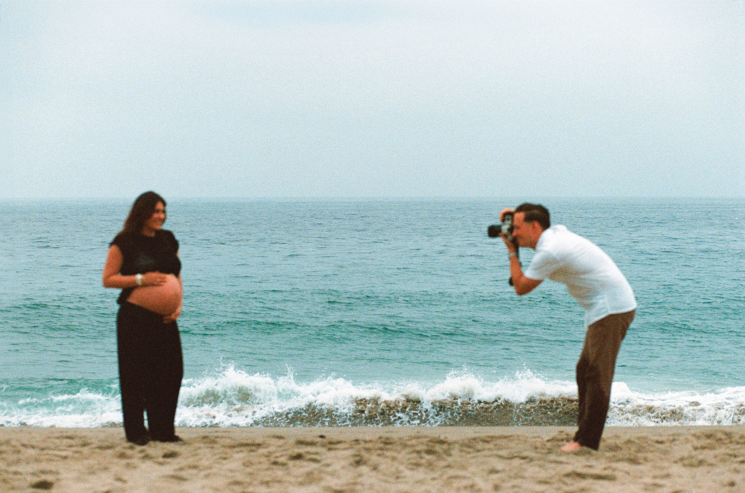 a husband takes a photo on film of his pregnant wife
