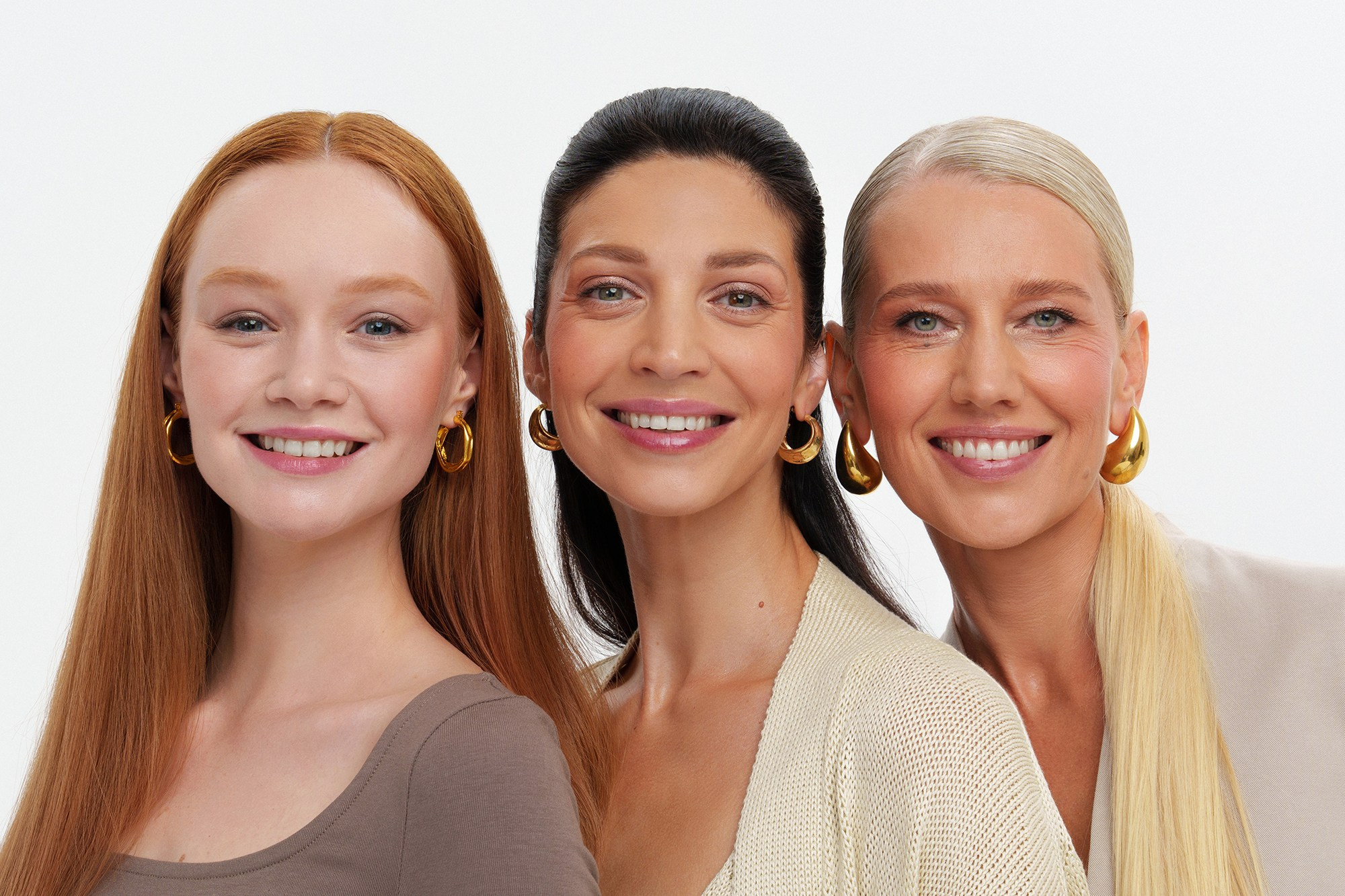 Три девушки разного возраста стоят рядом друг с другом и улыбаются 