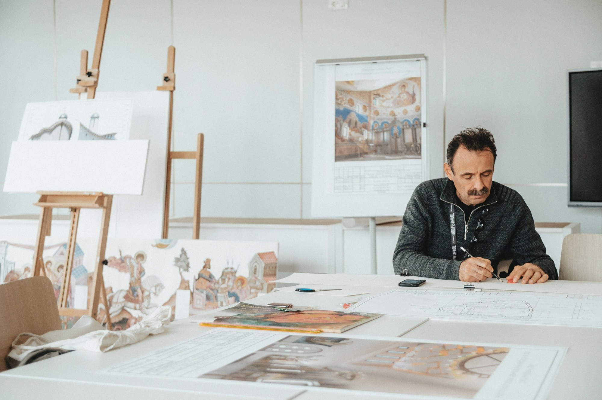 Съемка художника во время работы в своей мастерской на фоне других картин в Ростове-на-Дону
