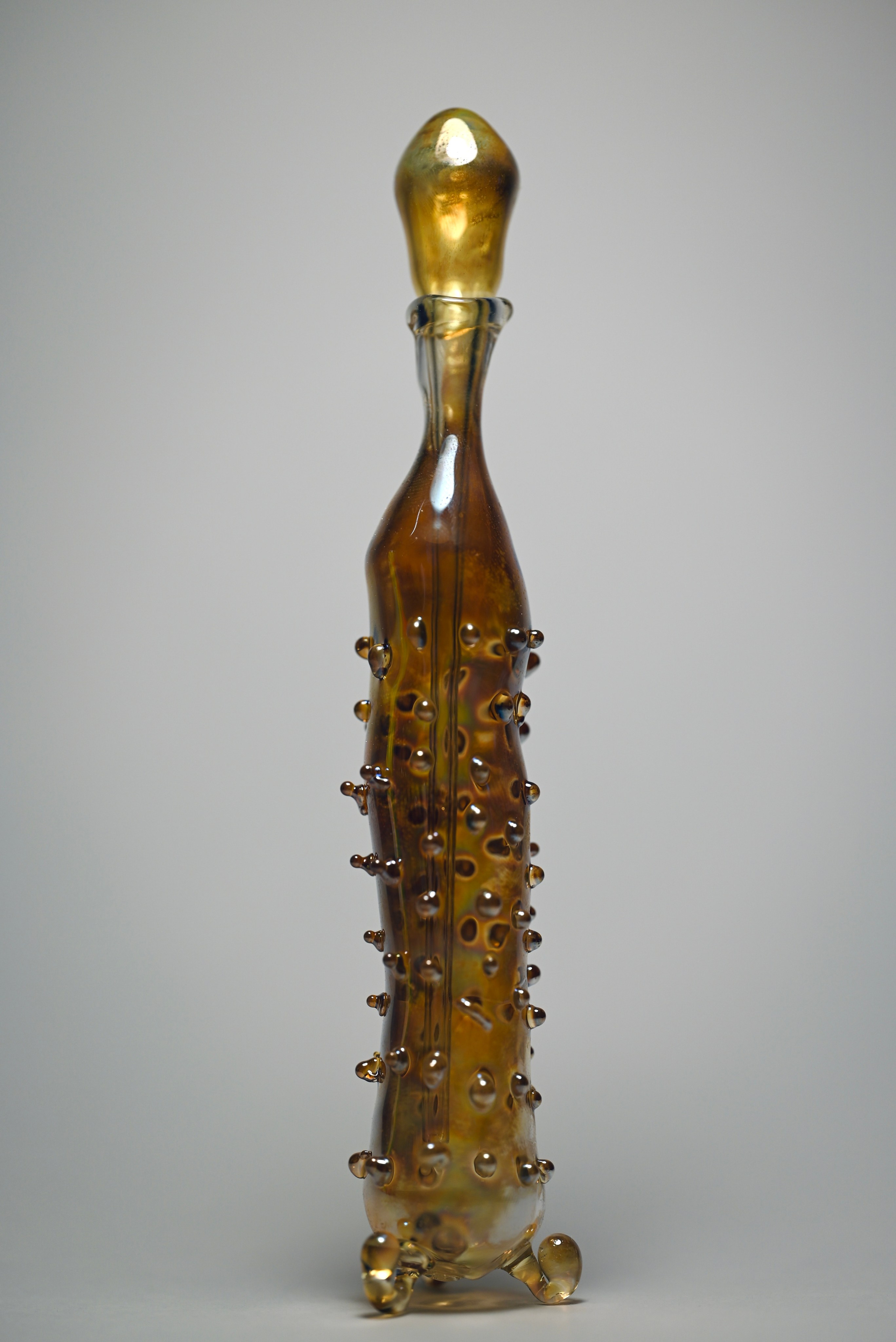 alt="Авторская стеклянная скульптура с прозрачной крышкой, янтарным корпусом и декоративными каплями на поверхности."