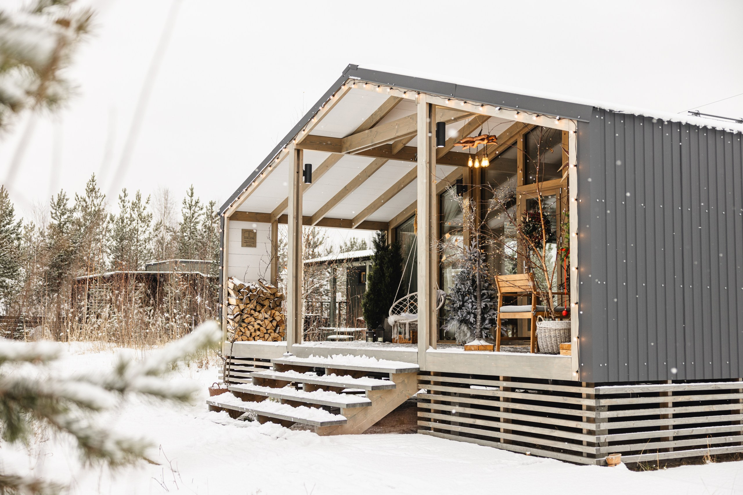 Фасад загородного дома 'Панорама' зимой, украшенный новогодними гирляндами и яркой иллюминацией