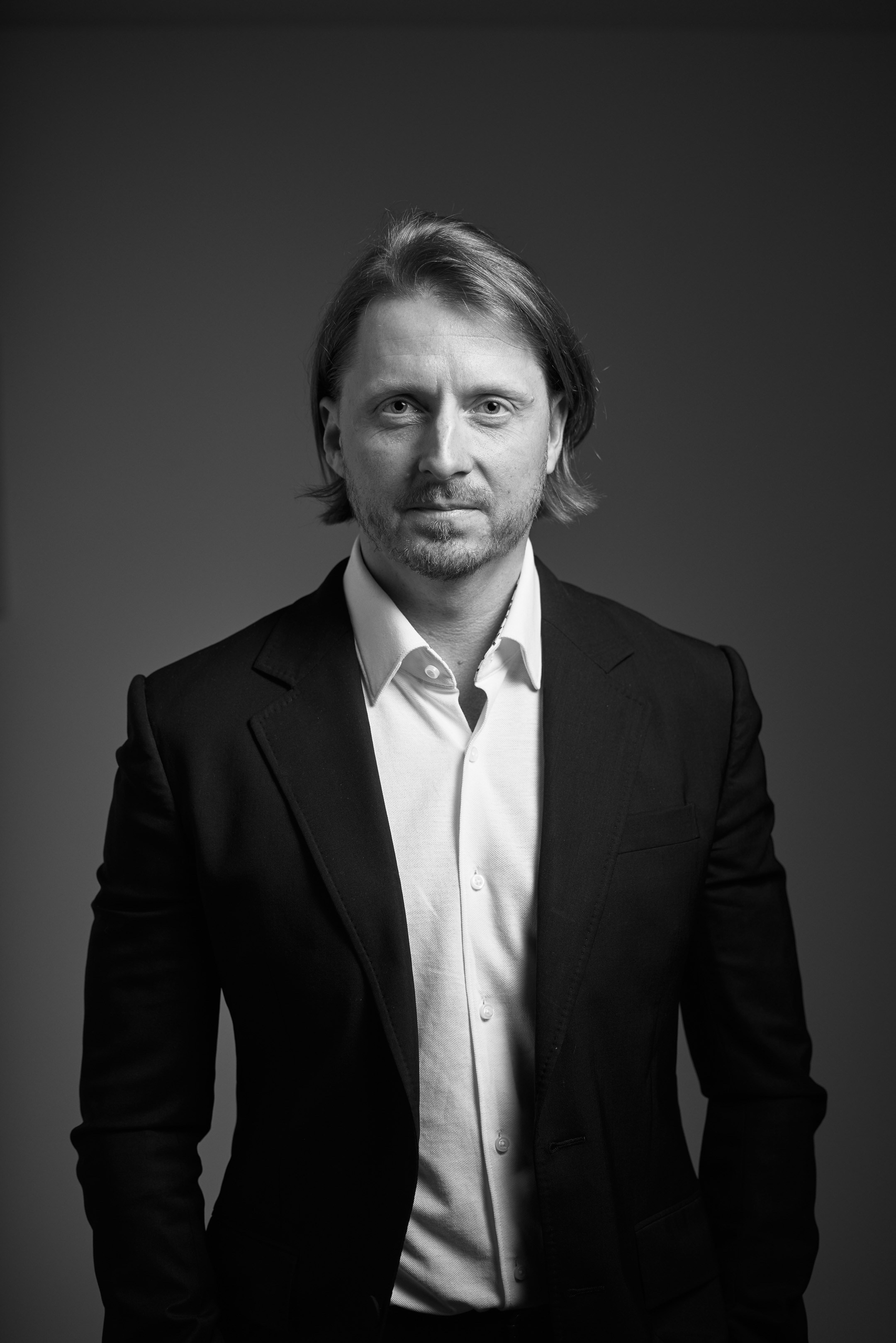 Black and white business portrait of a confident man in a suit on a dark studio background