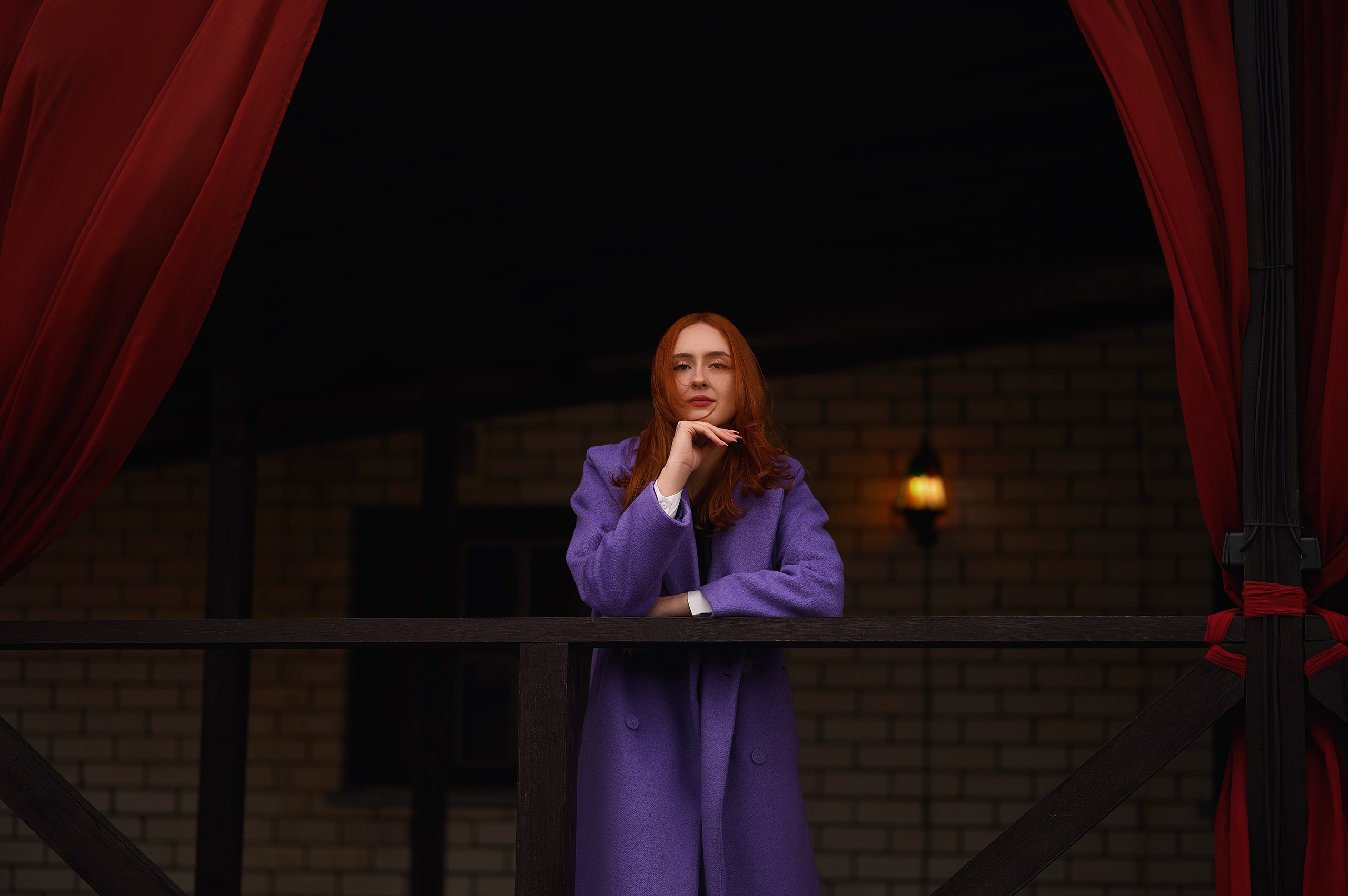 Девушка с рыжими волосами в фиолетовом пальто. Съёмка на фоне здания с красными шторами. Фотограф — Елизавета Жуйкова, Волгодонск.